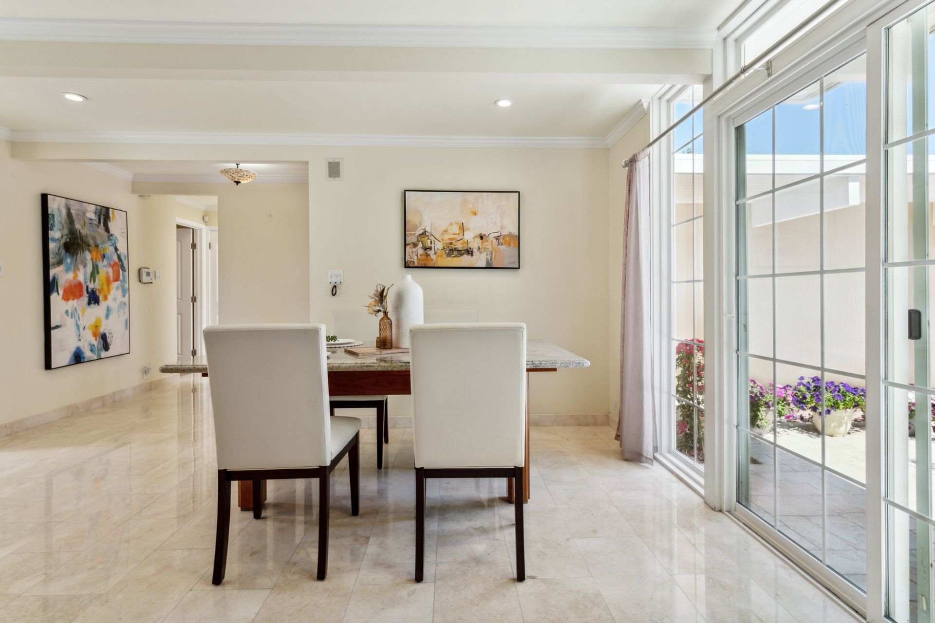A dining room with a table and chairs and a sliding glass door.
