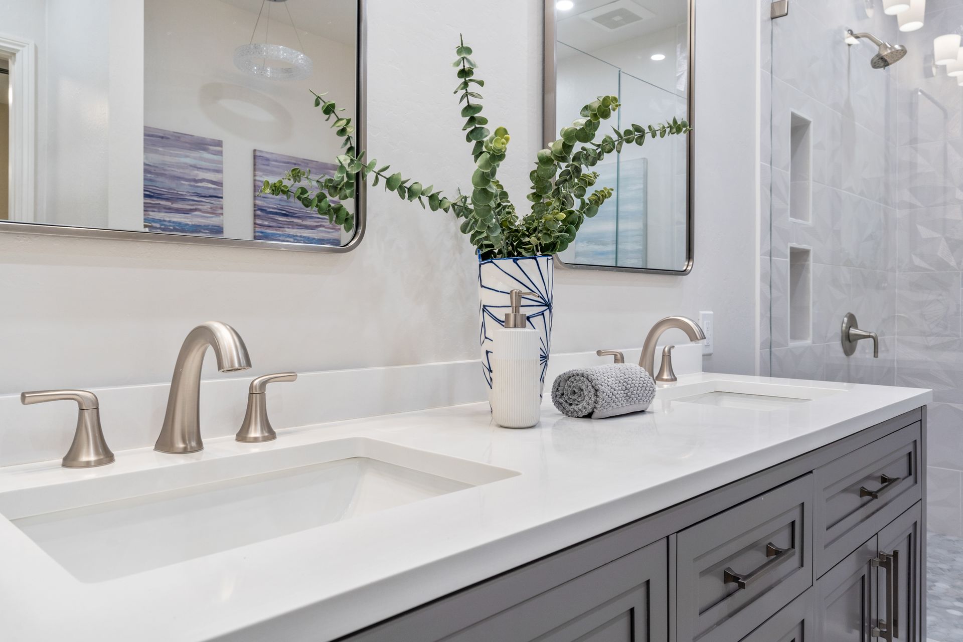 A bathroom with two sinks , a mirror , and a vase of flowers.