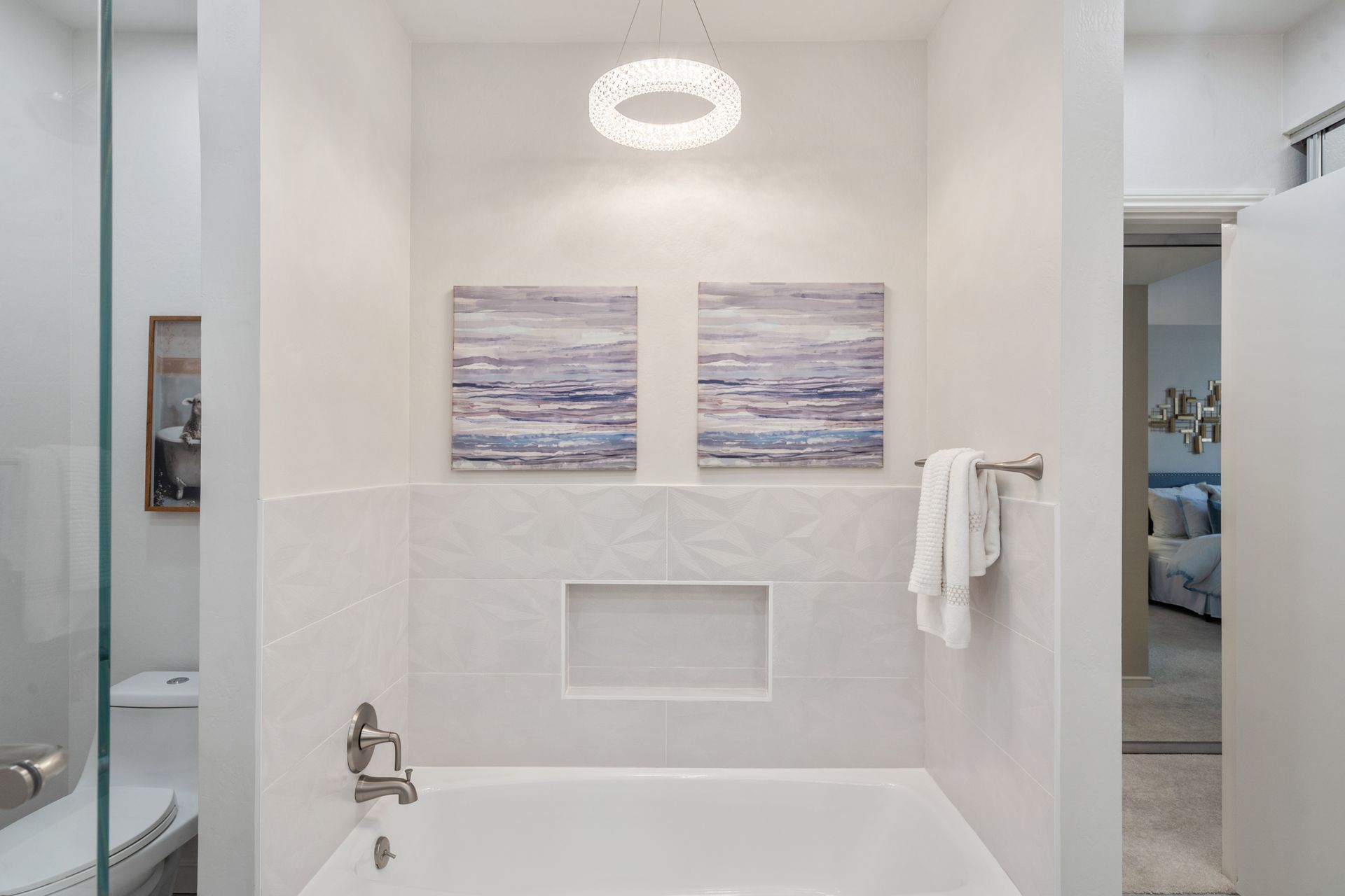 A bathroom with a bathtub and two paintings on the wall.