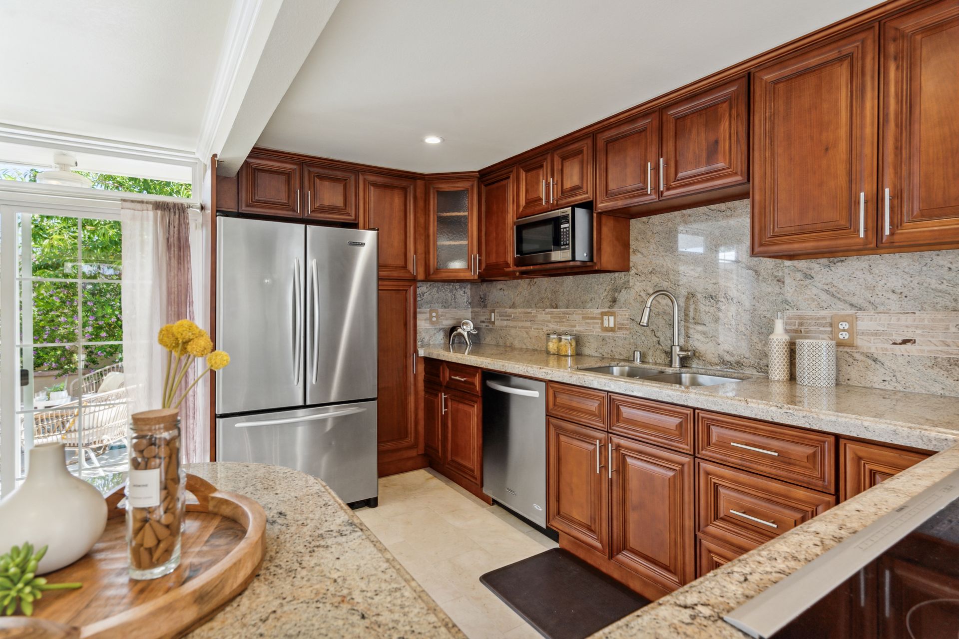 A kitchen with wooden cabinets , granite counter tops , stainless steel appliances and a refrigerator.