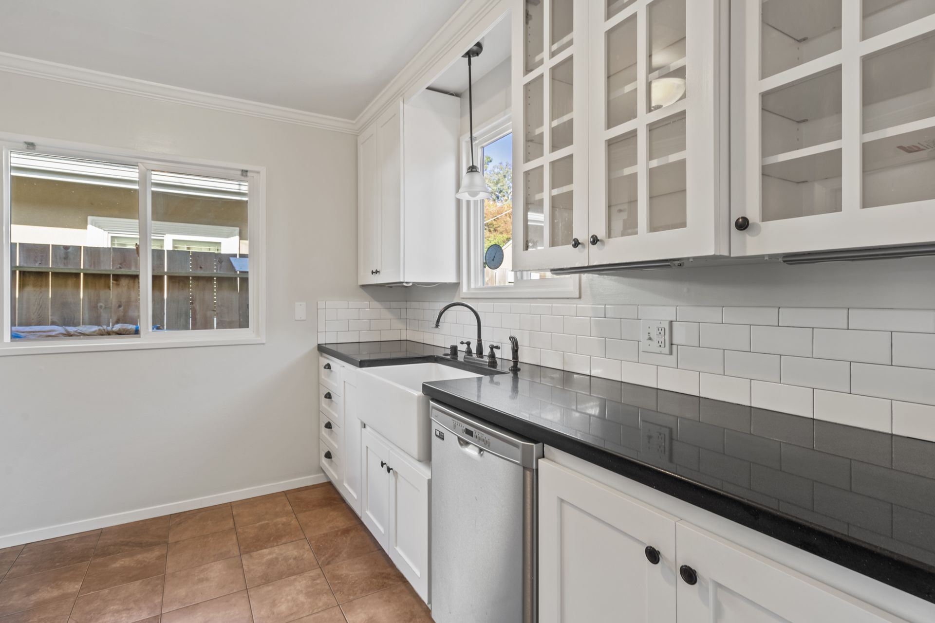 A kitchen with white cabinets , black counter tops , a sink and a dishwasher.
