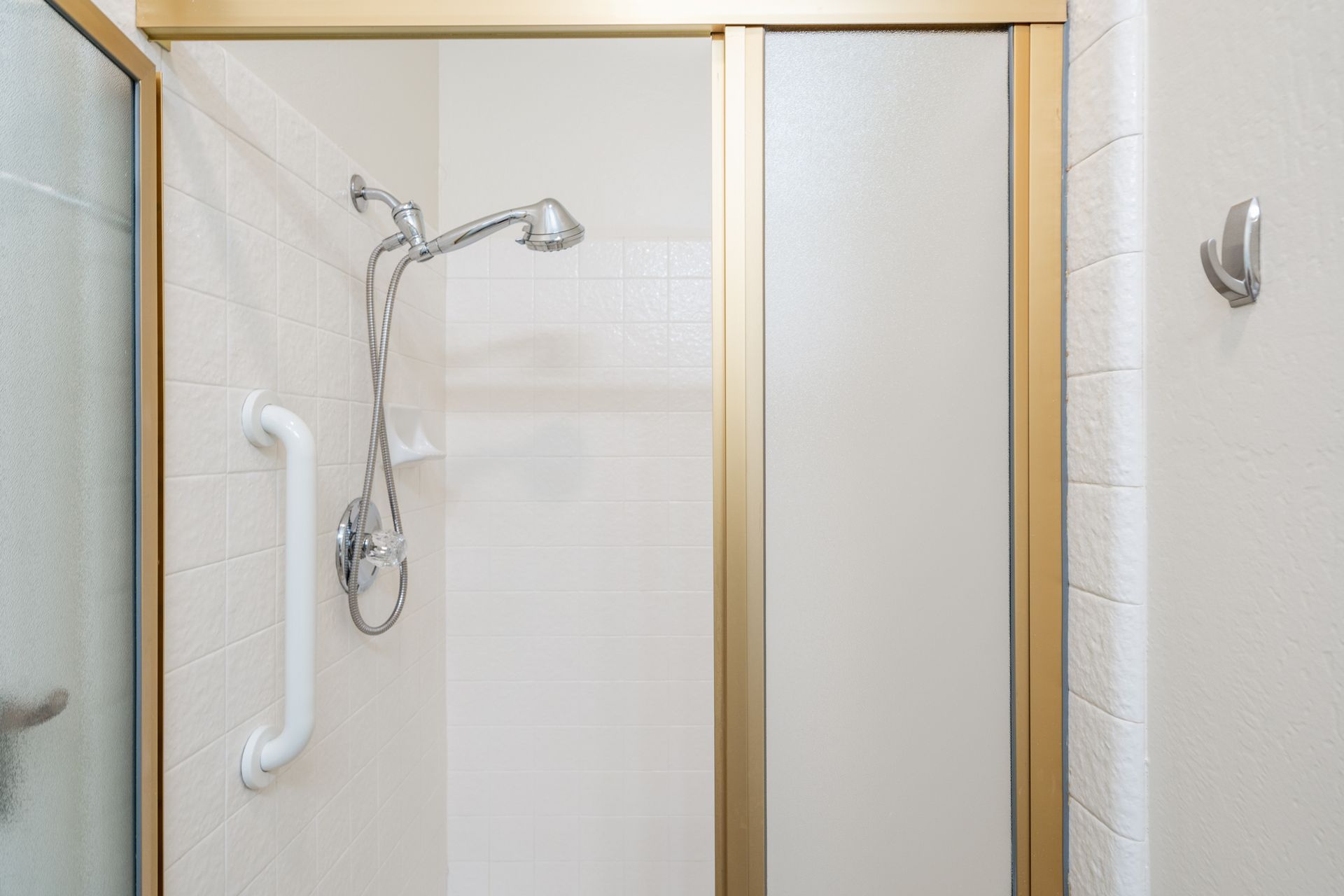 A bathroom with a sliding glass shower door and a shower head.