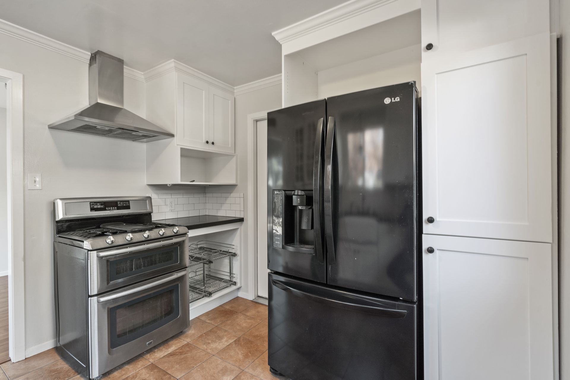 A kitchen with a black refrigerator , stove , and microwave.
