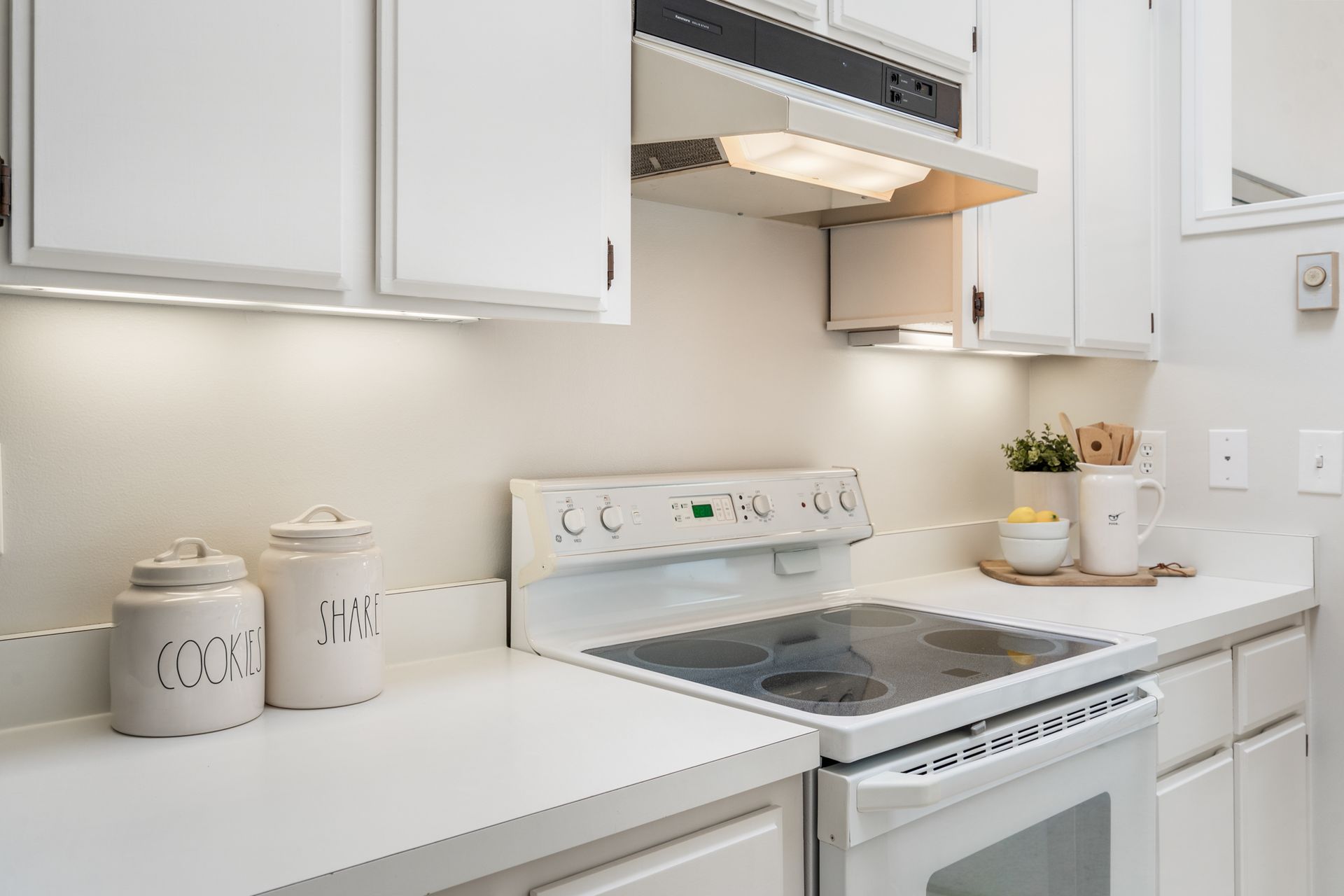 A kitchen with white cabinets , a stove top oven , and a hood.