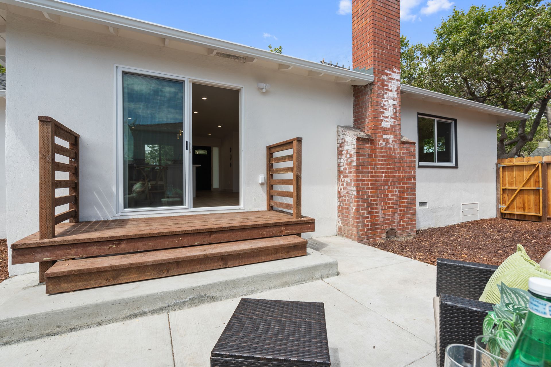 A white house with a sliding glass door and a brick chimney.