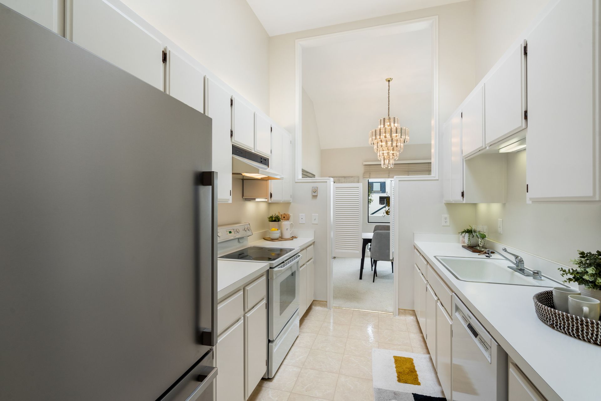 A kitchen with white cabinets and a stainless steel refrigerator