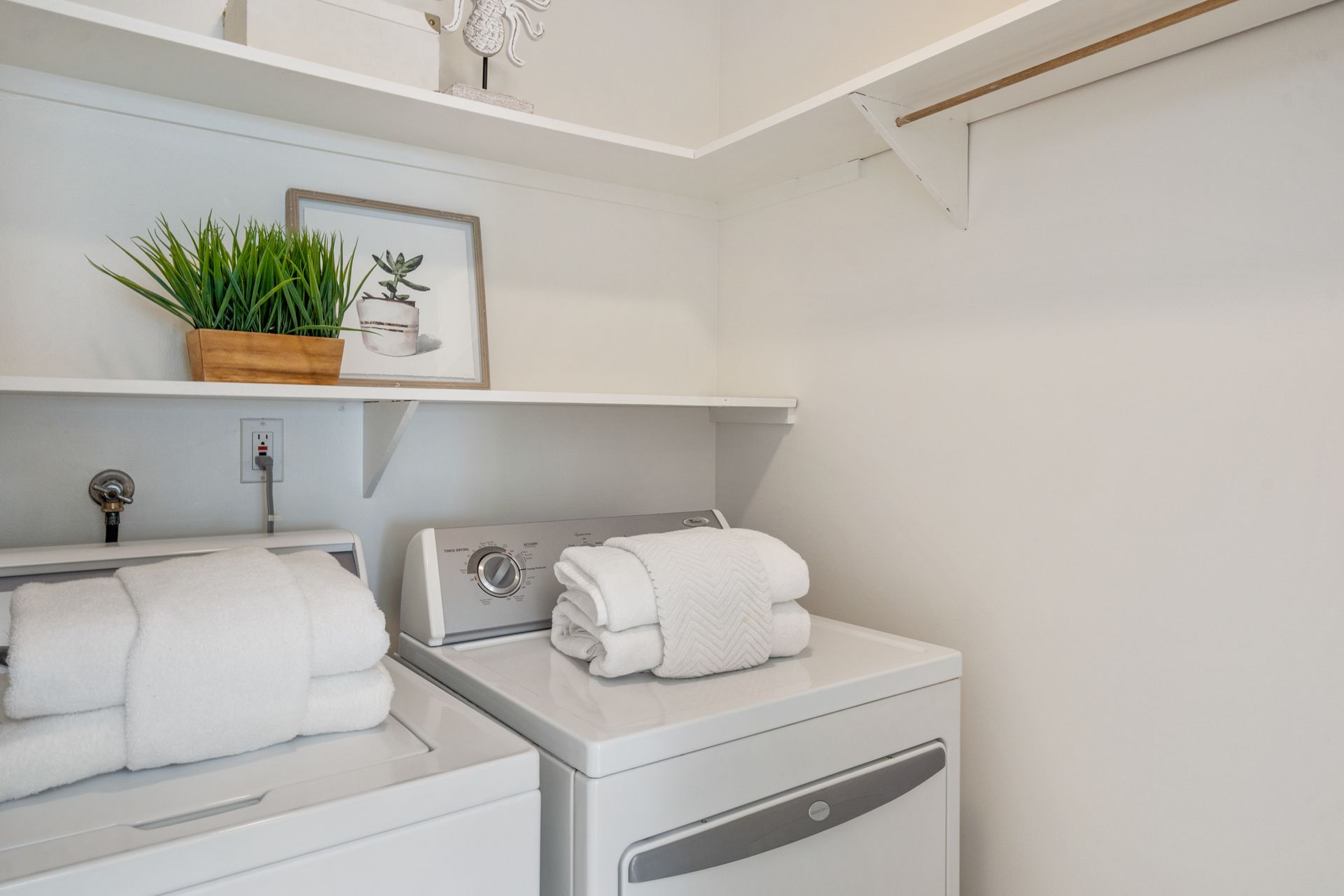 A laundry room with a washer and dryer and a shelf.