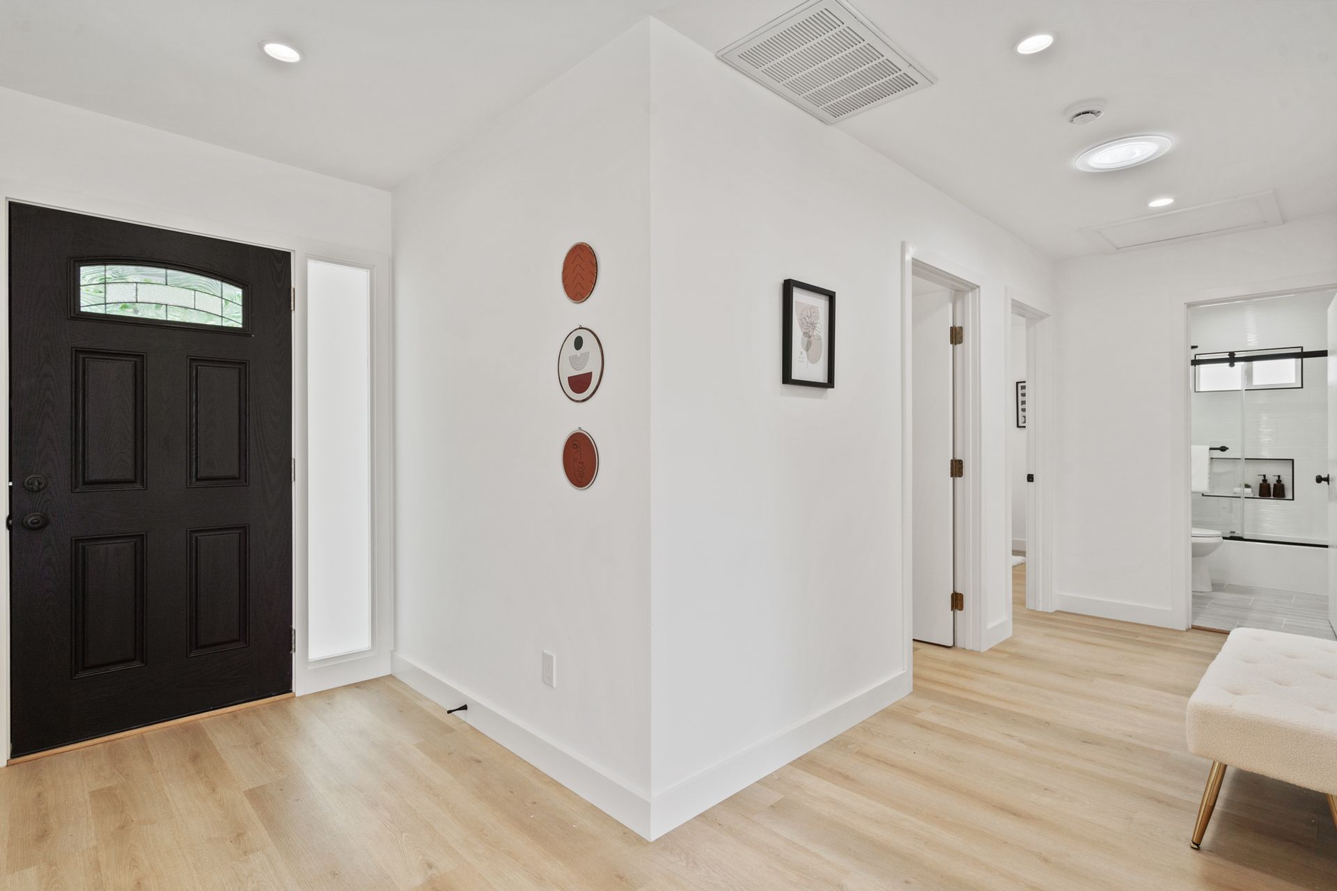 A hallway with a black door and wooden floors in a house.