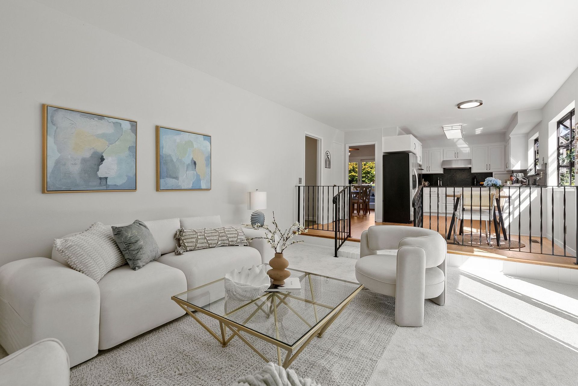 A living room with white furniture and a glass coffee table.