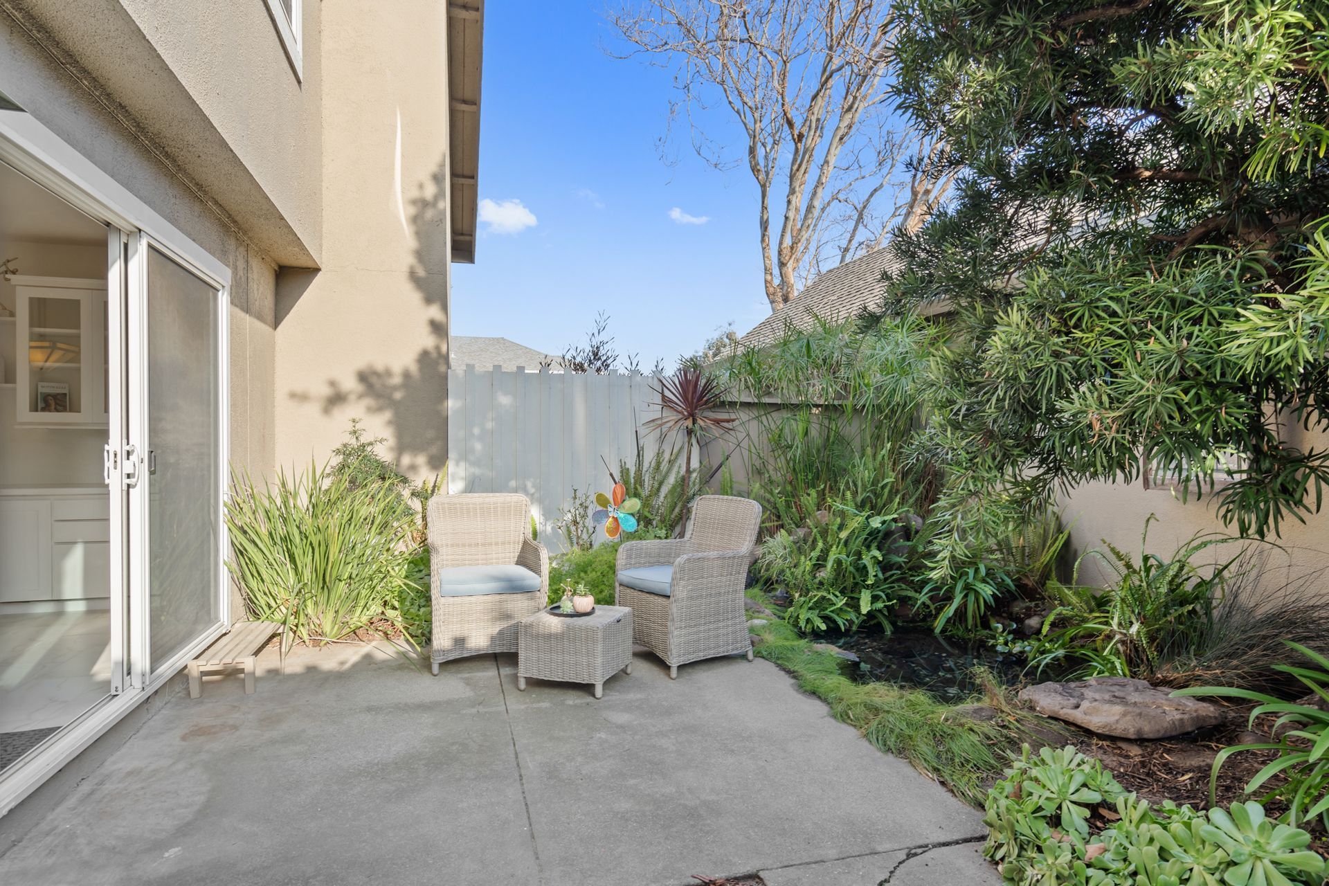 A patio with chairs and a table in front of a house.