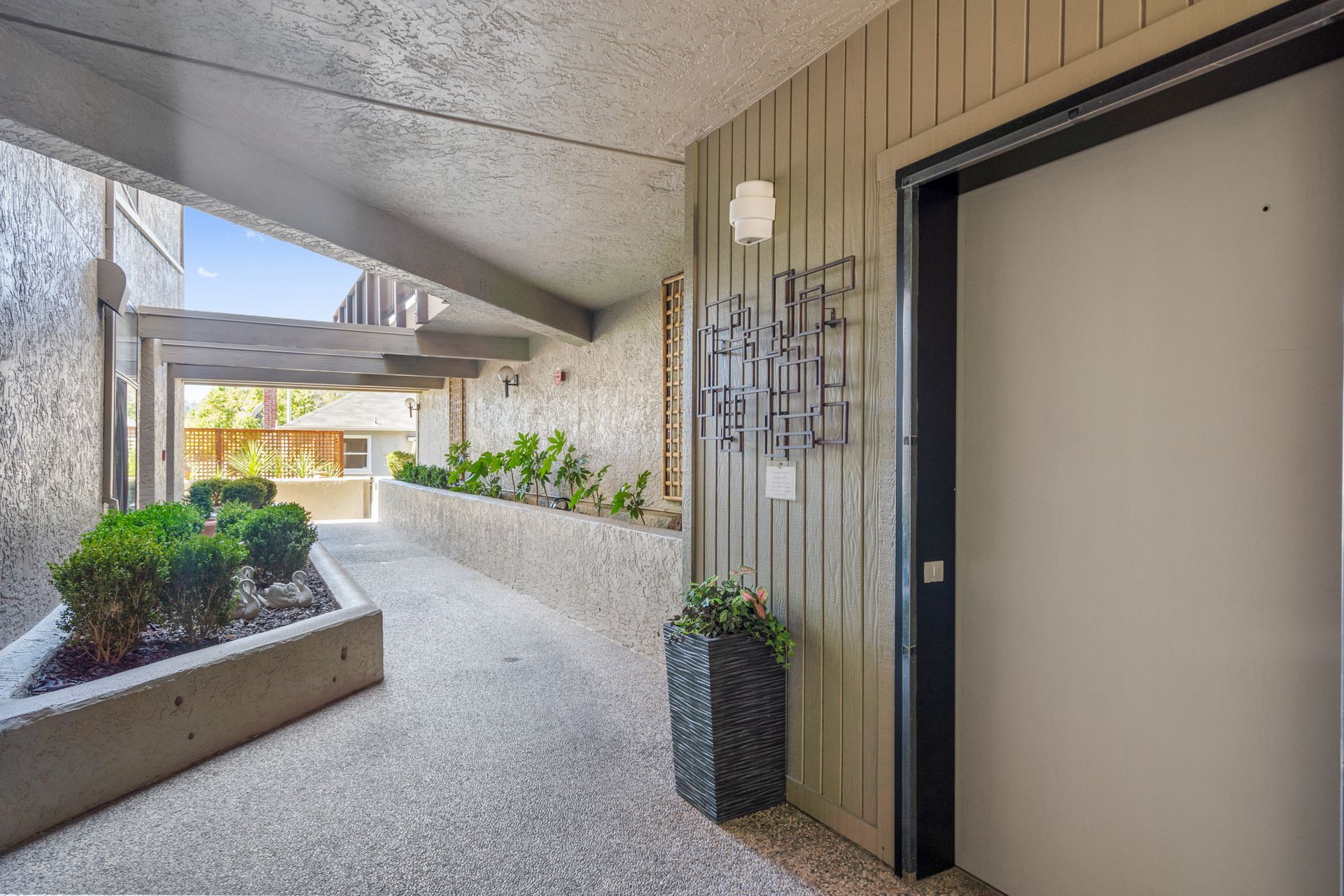 A hallway in a building with a door and planters.