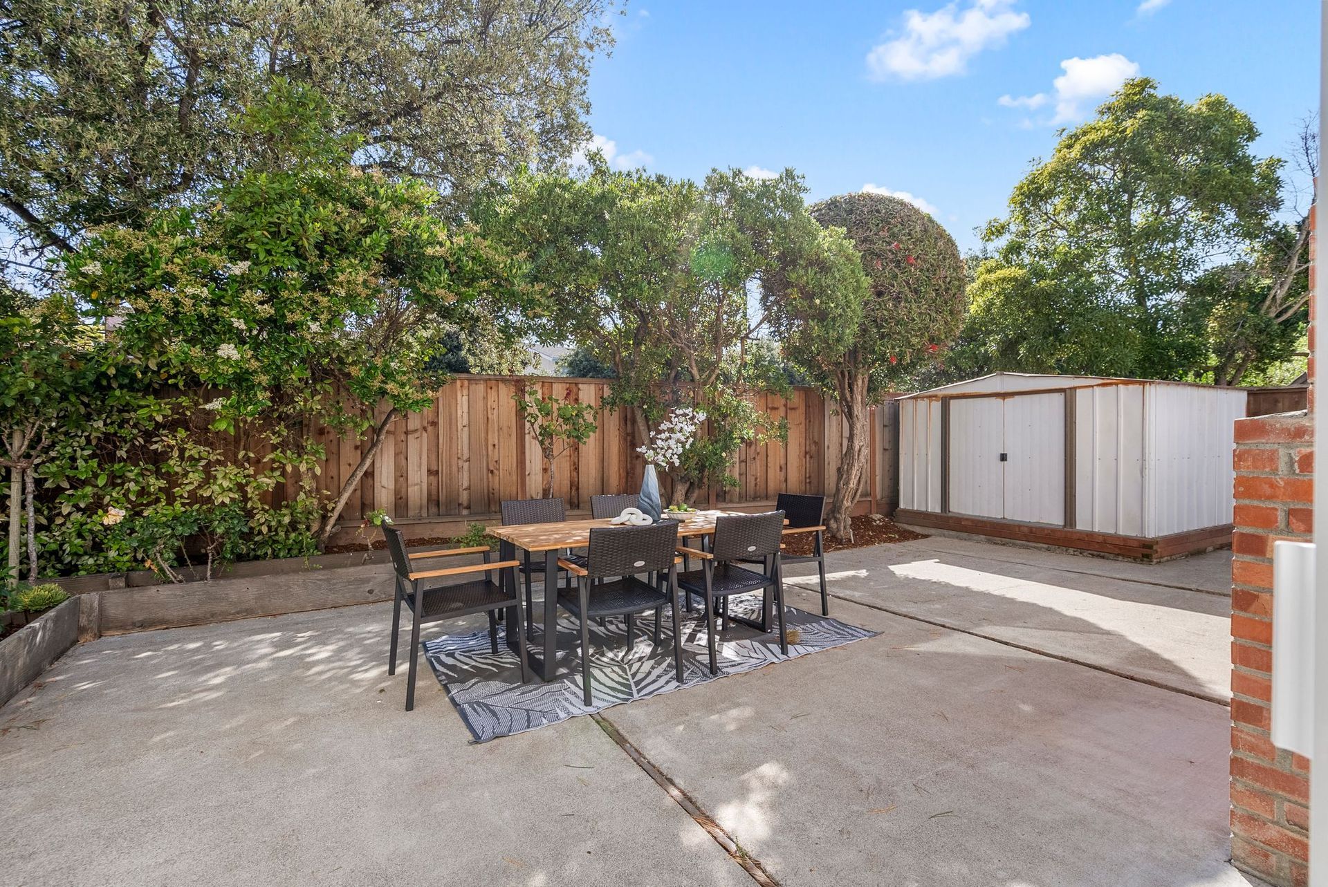 There is a table and chairs in the backyard of a house.