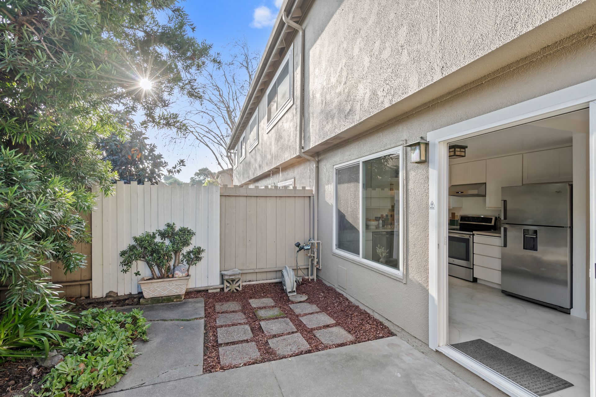 A house with a patio and sliding glass doors leading to a kitchen.