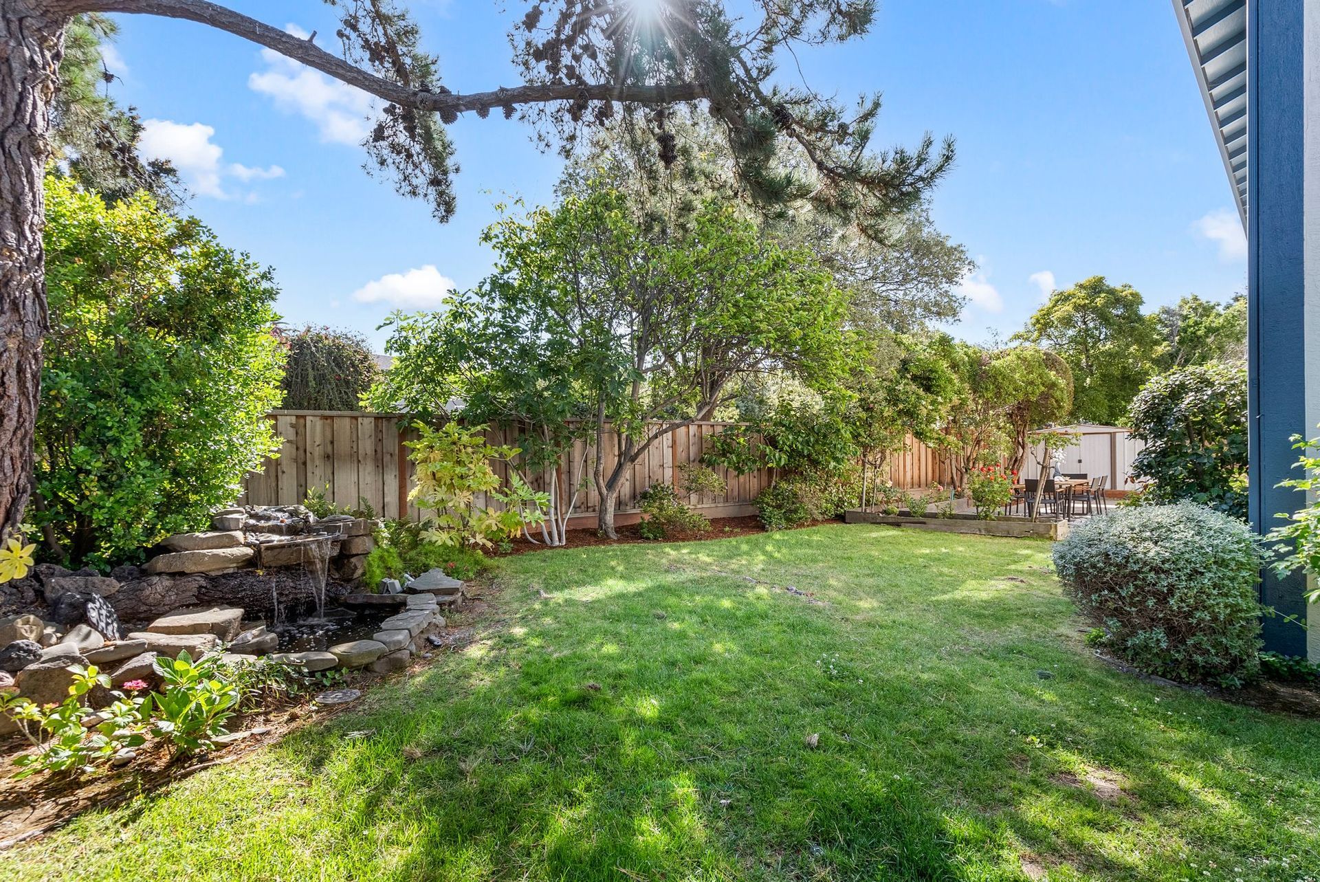 A large lush green yard with a fountain in the middle of it.
