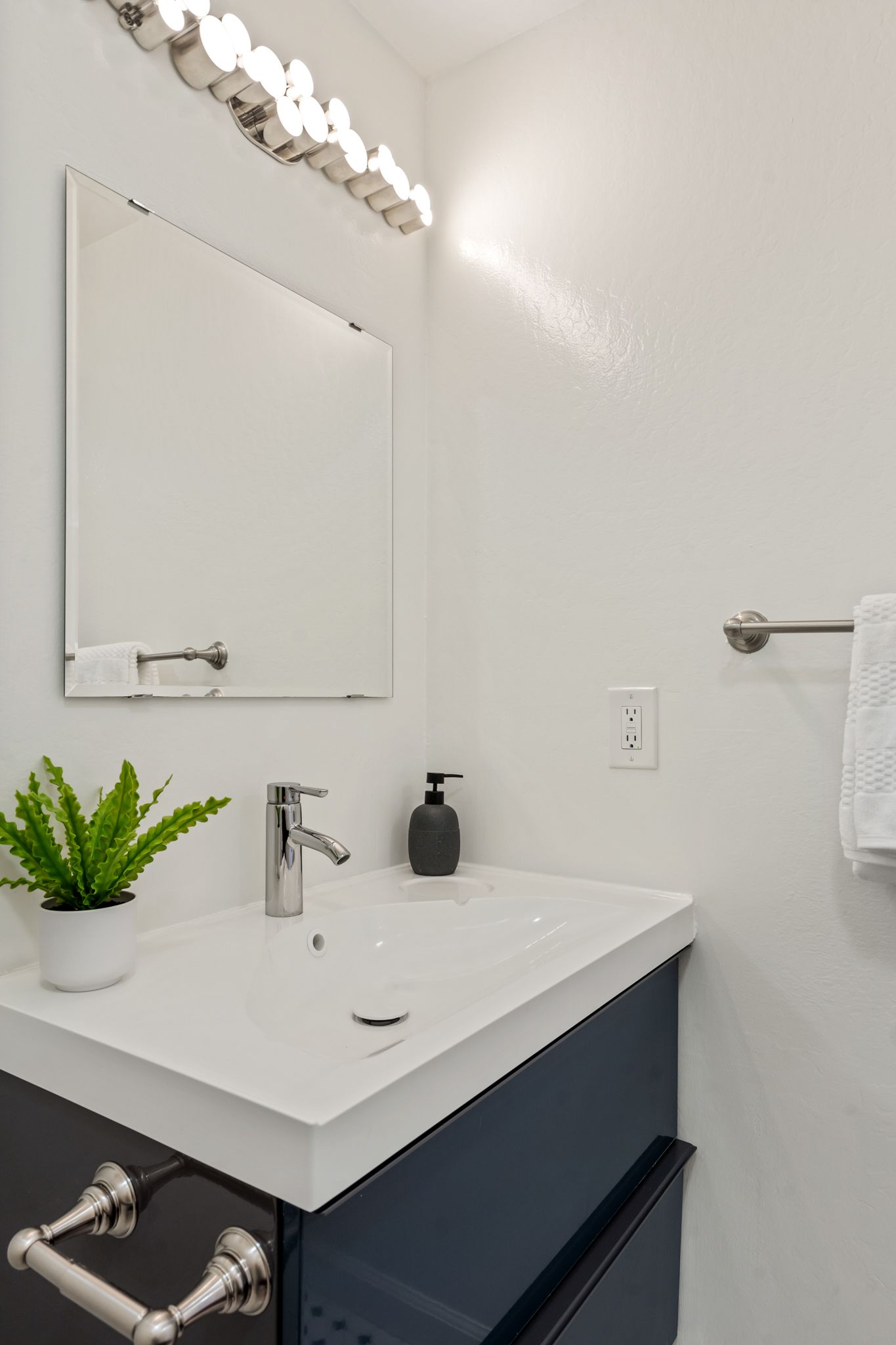 A bathroom with a sink , mirror and towel rack.