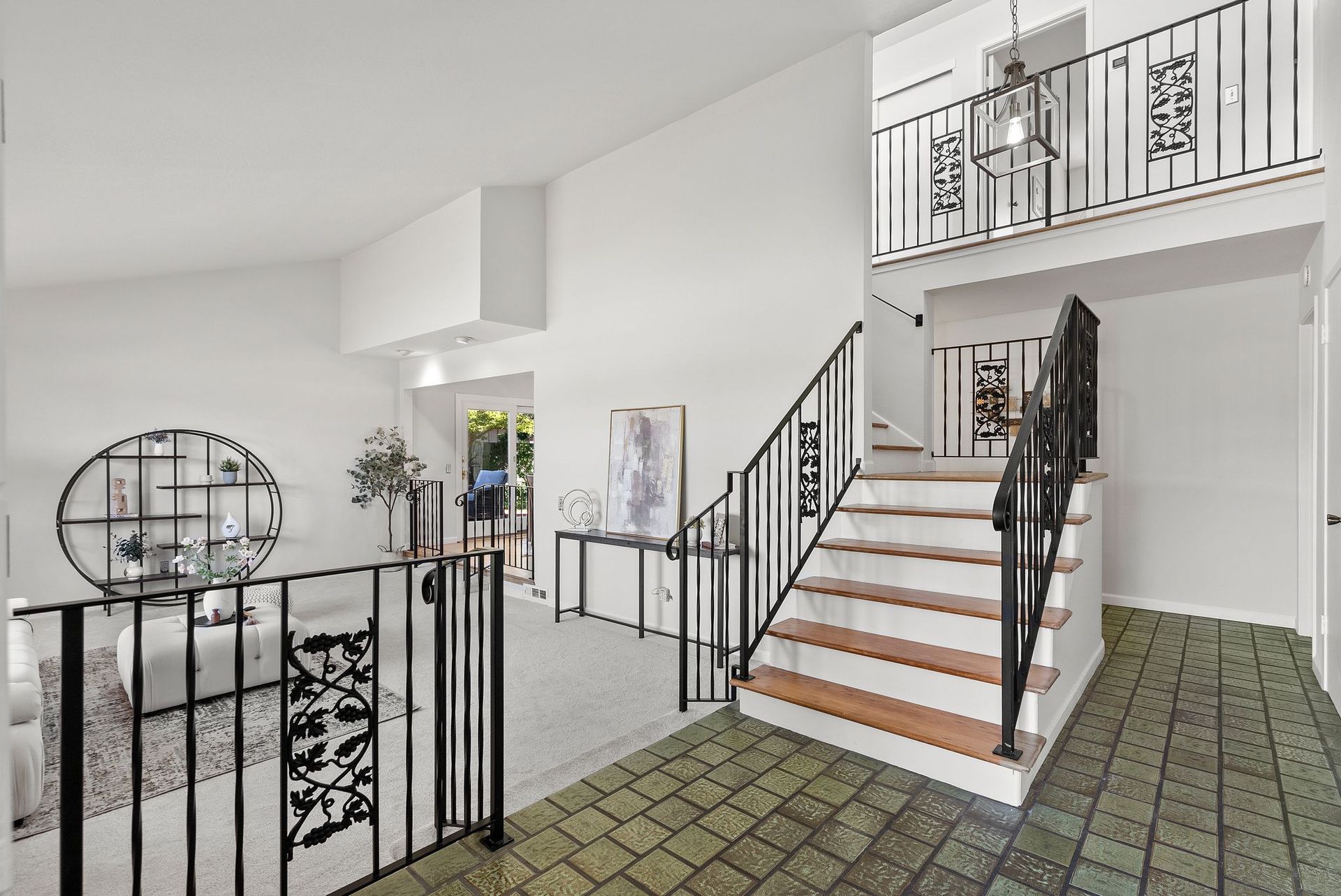 A staircase in a house with a wrought iron railing leading up to the second floor.