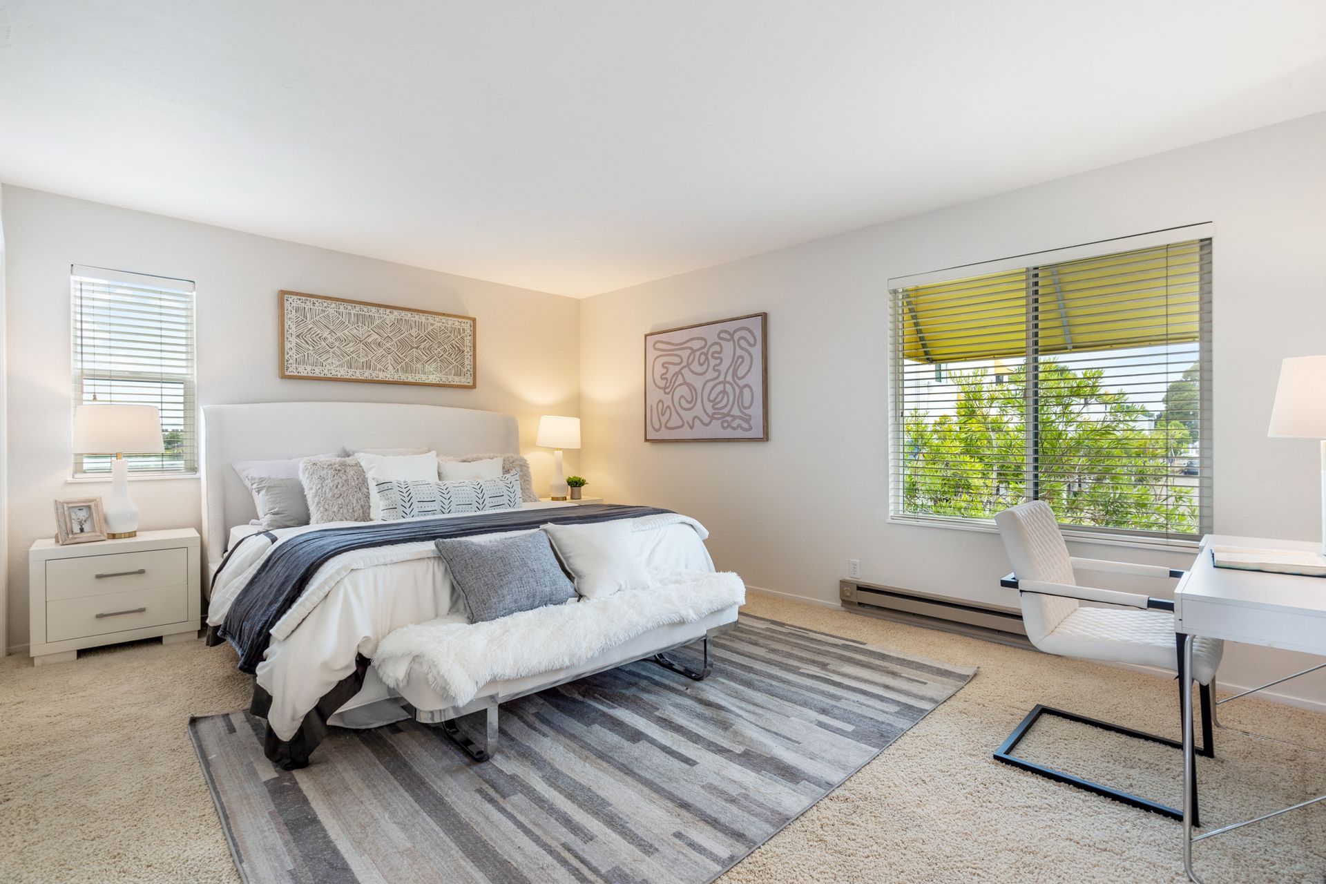 A bedroom with a king size bed , a desk , and a large window.