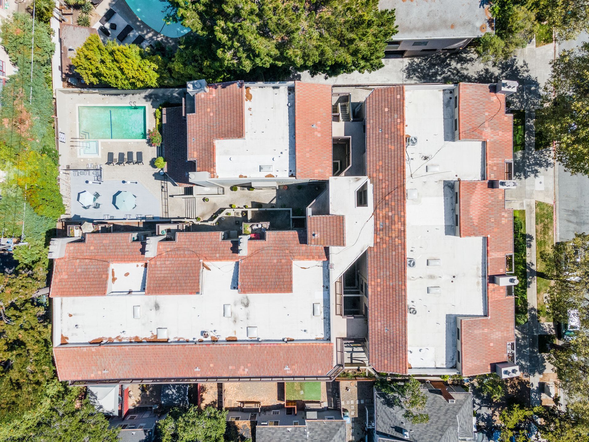 An aerial view of a building with a pool in the backyard