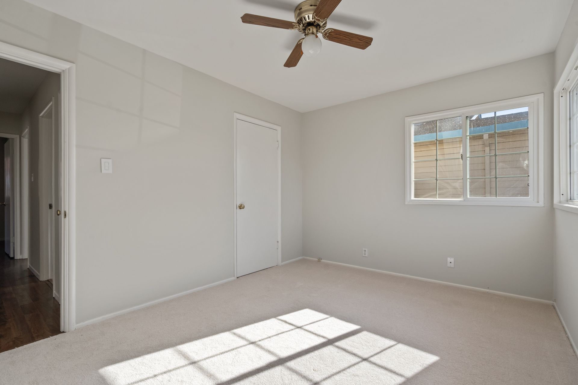 An empty bedroom with a ceiling fan and a window.