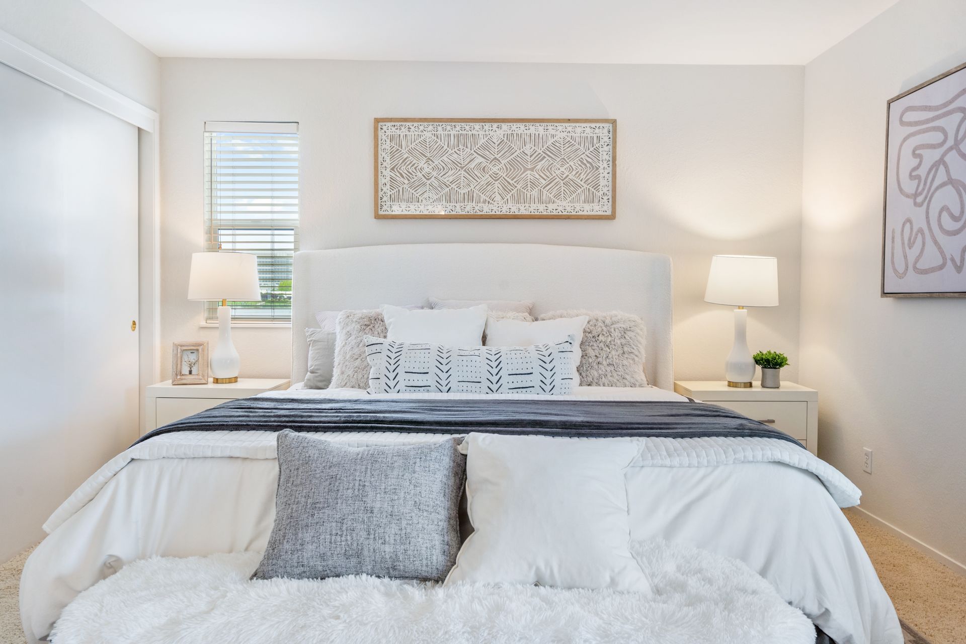 A bedroom with a bed , nightstands , lamps and a window.
