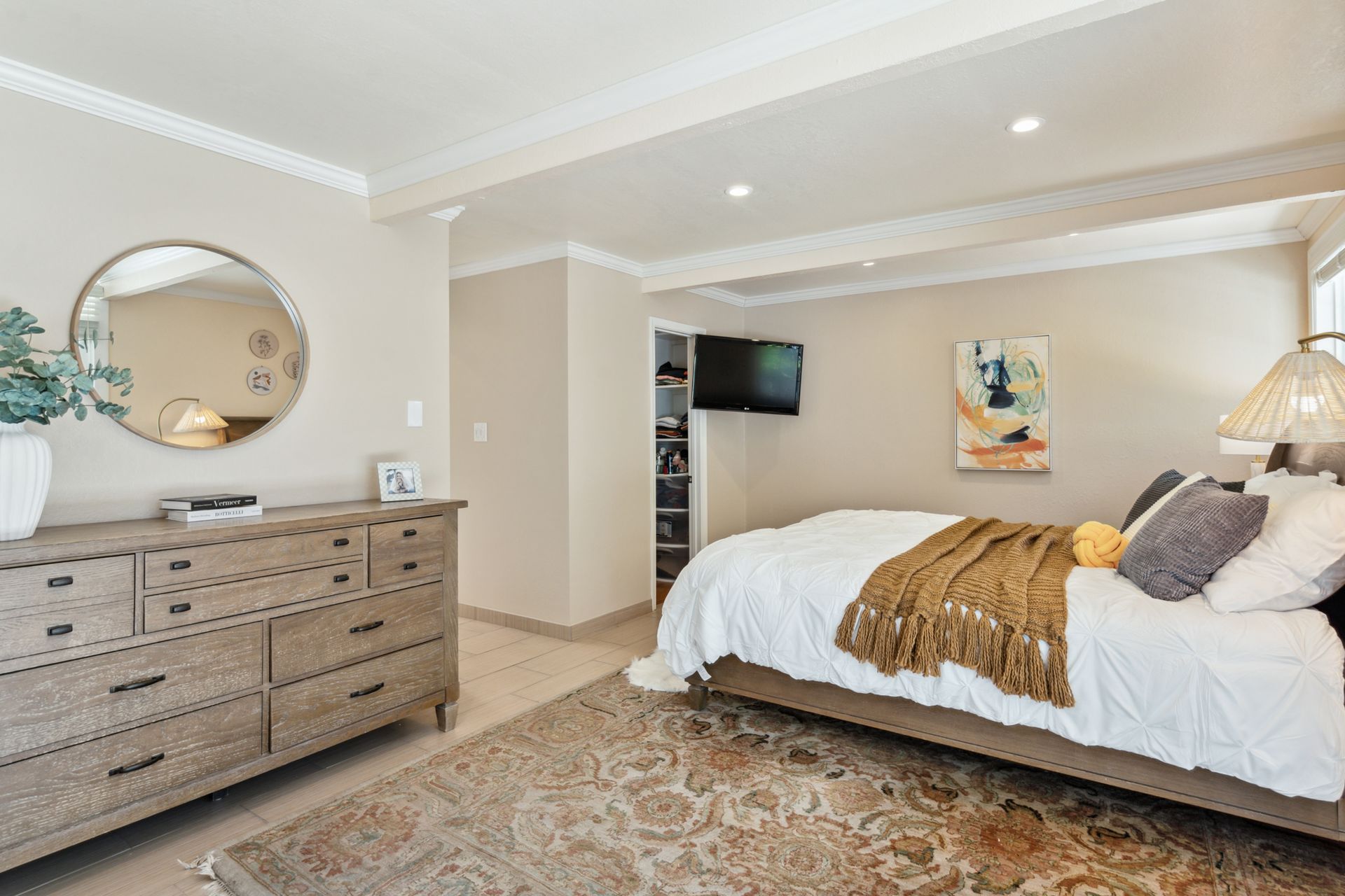 A bedroom with a bed , dresser , mirror and rug.