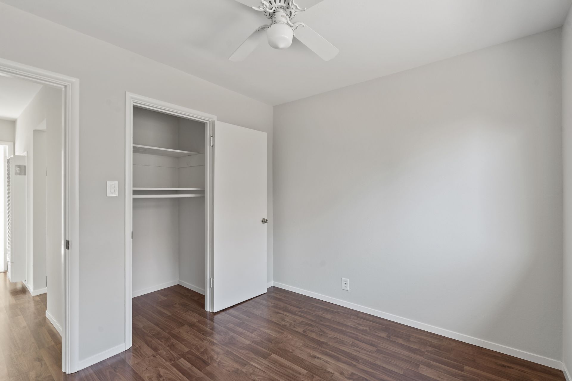 An empty bedroom with a ceiling fan and a closet.