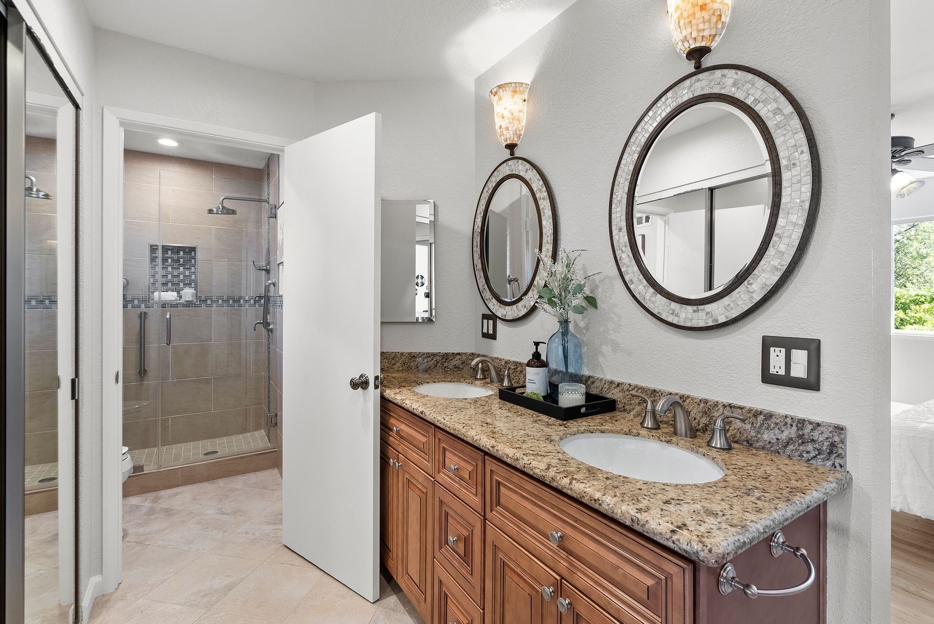A bathroom with two sinks , two mirrors and a walk in shower.