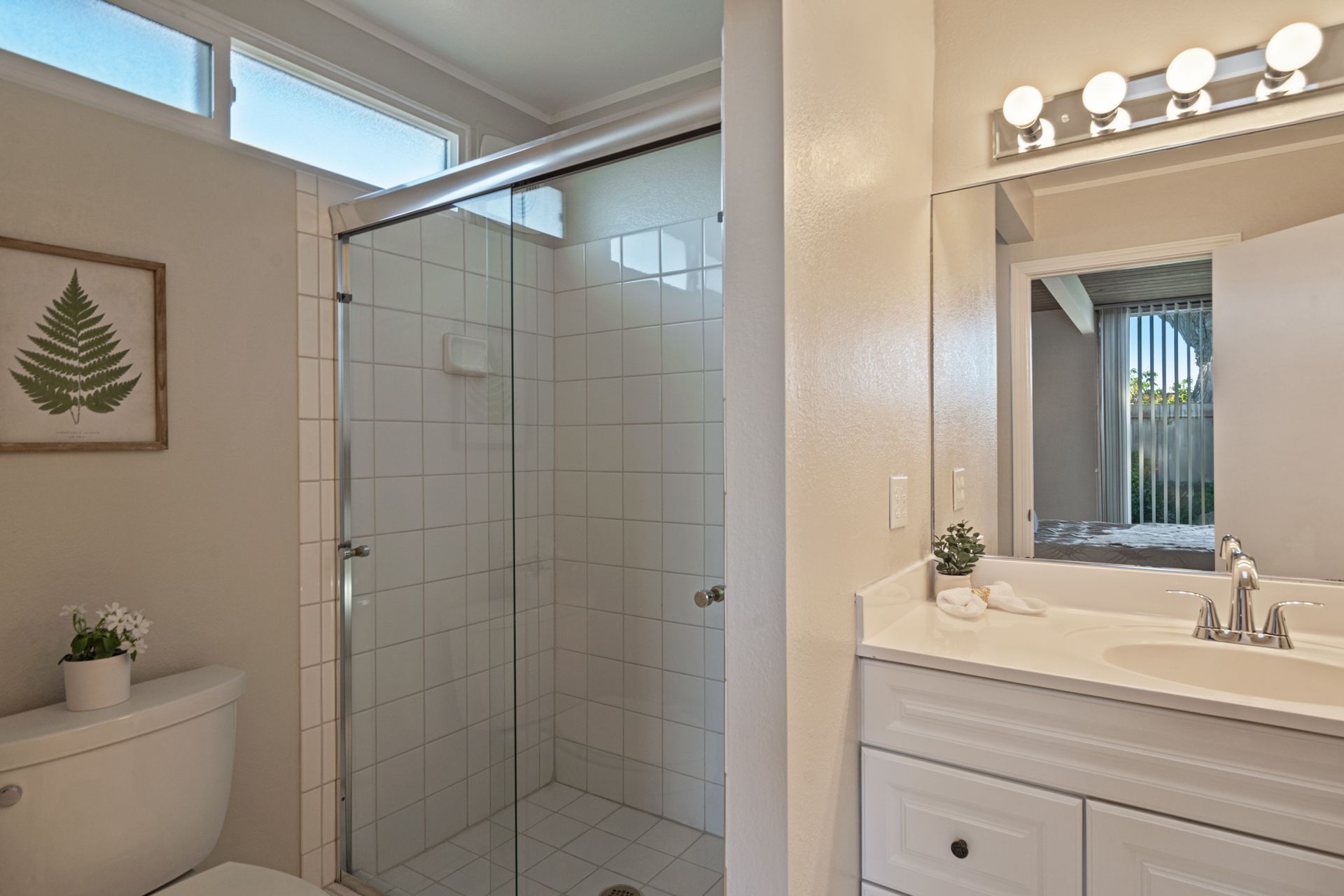 A bathroom with a toilet , sink , shower and mirror.