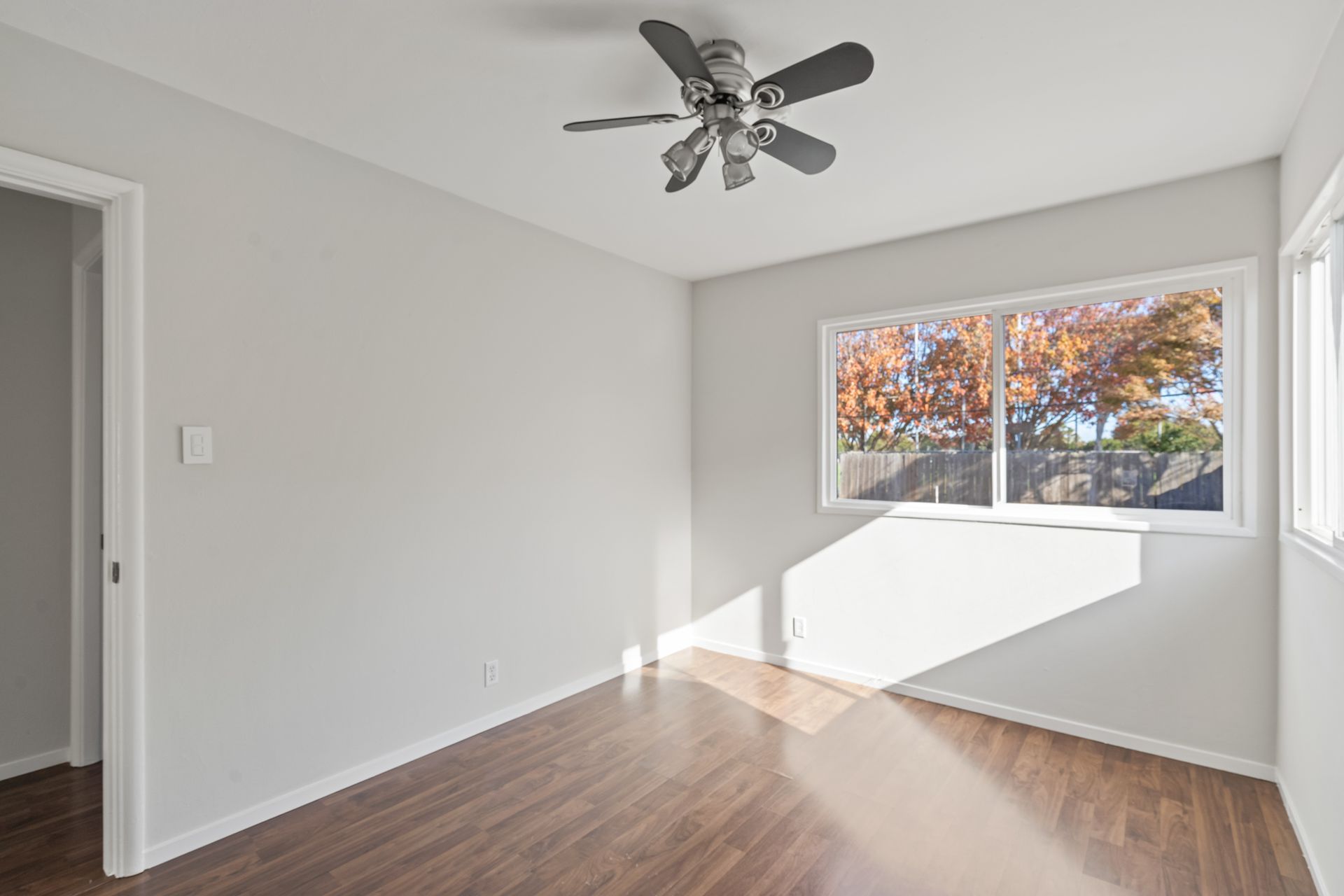 An empty room with a ceiling fan and a window.