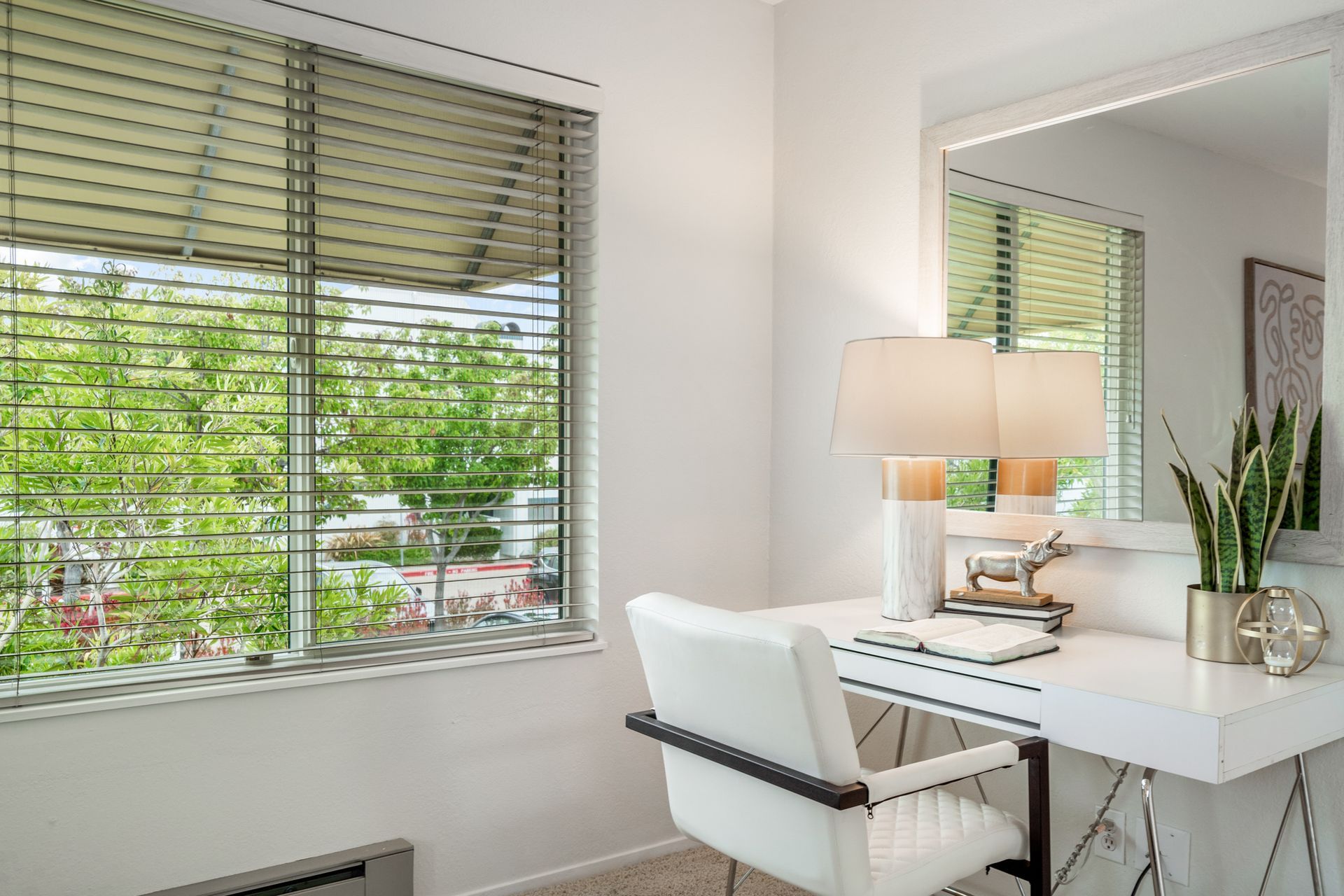 There is a desk with a chair and a mirror in the room.