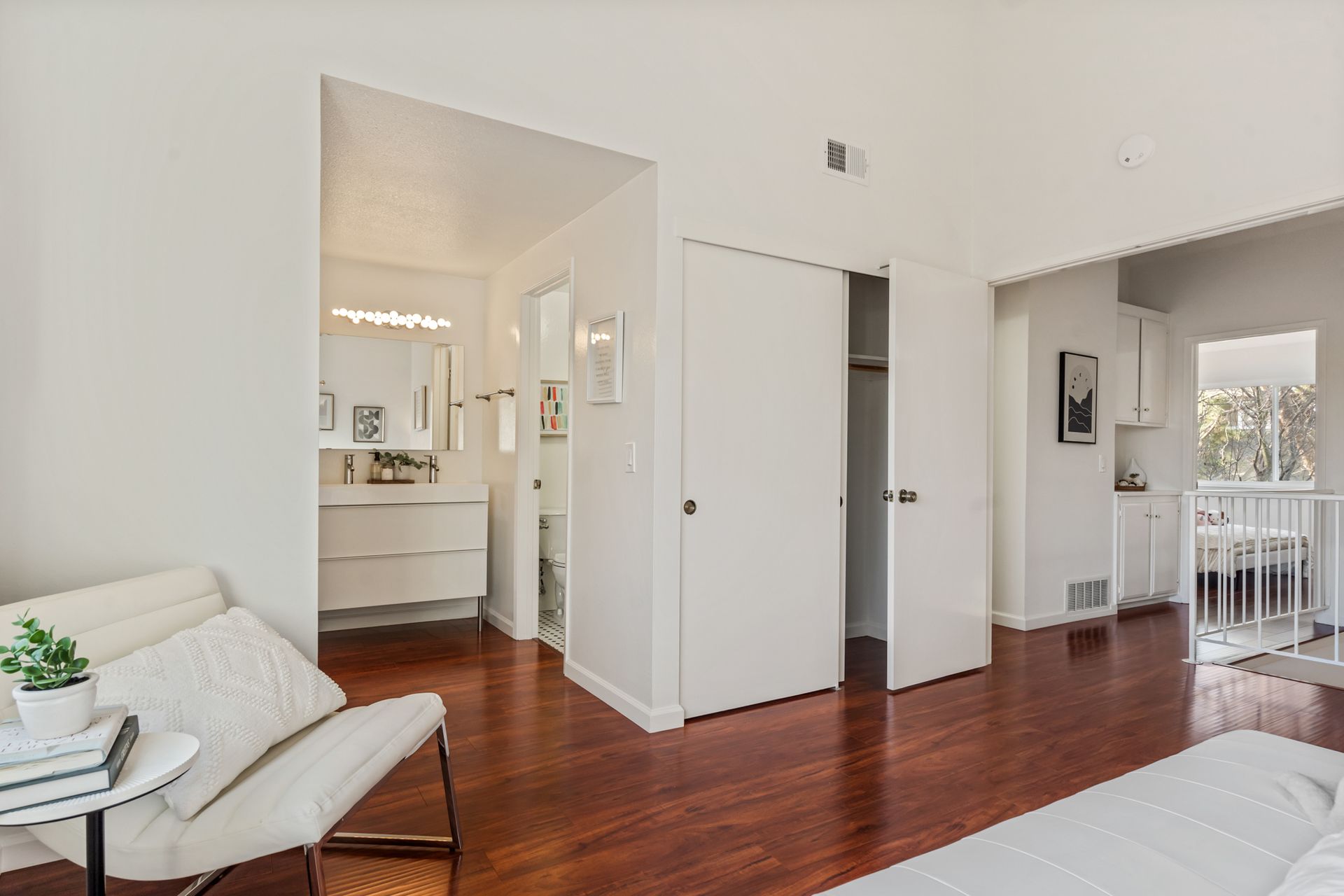 A living room with hardwood floors , a couch , a chair and a closet.