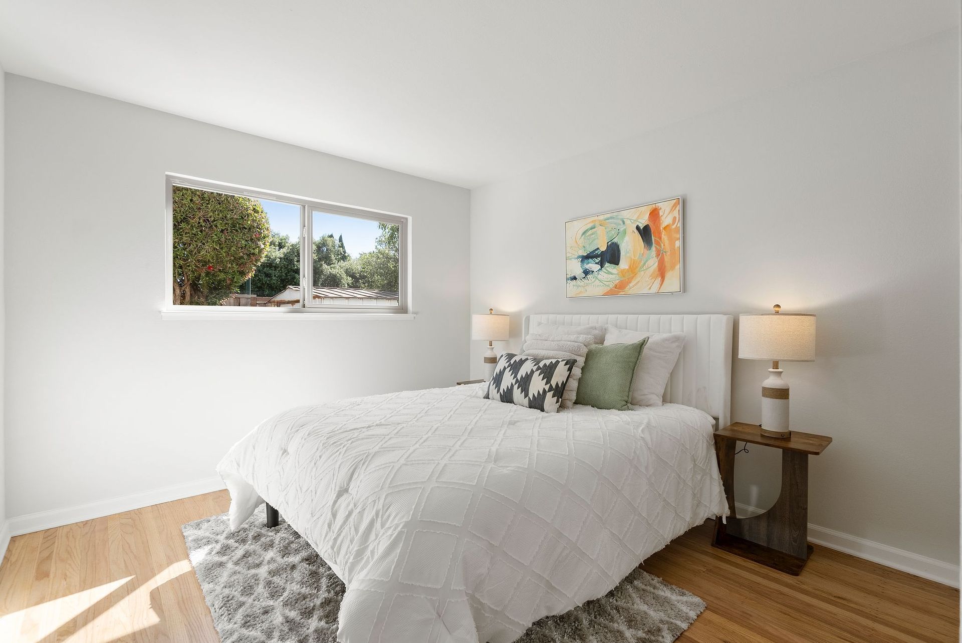 A bedroom with a bed , lamps , and a window.