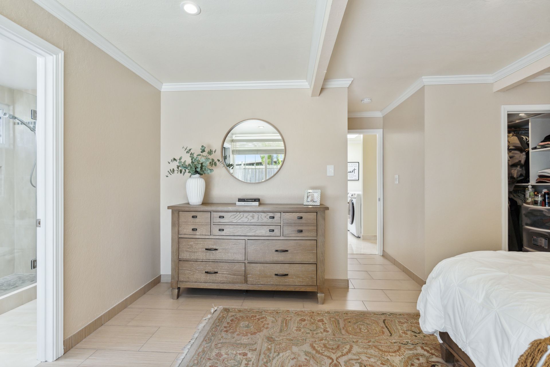 A bedroom with a bed , dresser , mirror and rug.