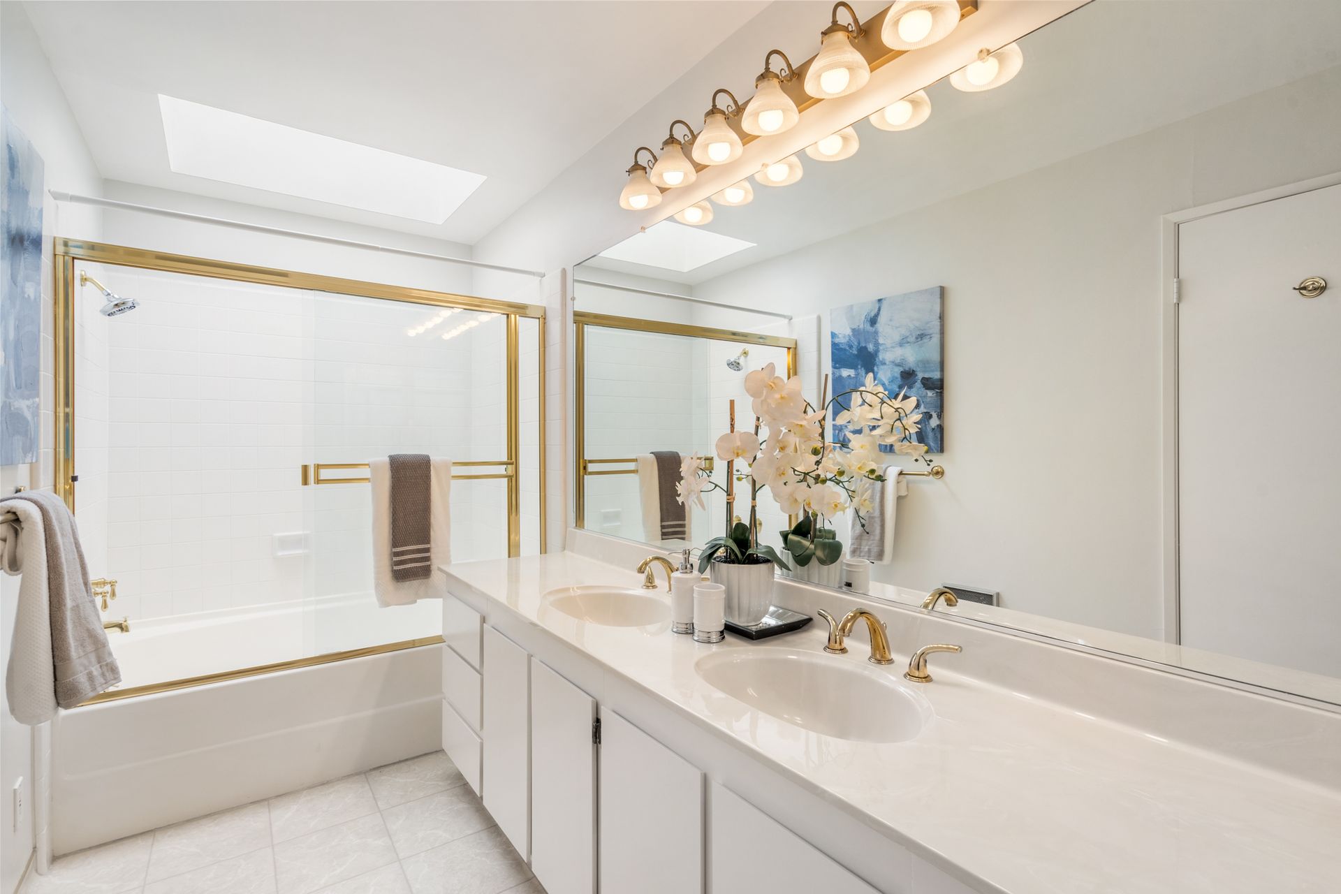 A bathroom with two sinks , a tub , and a large mirror.