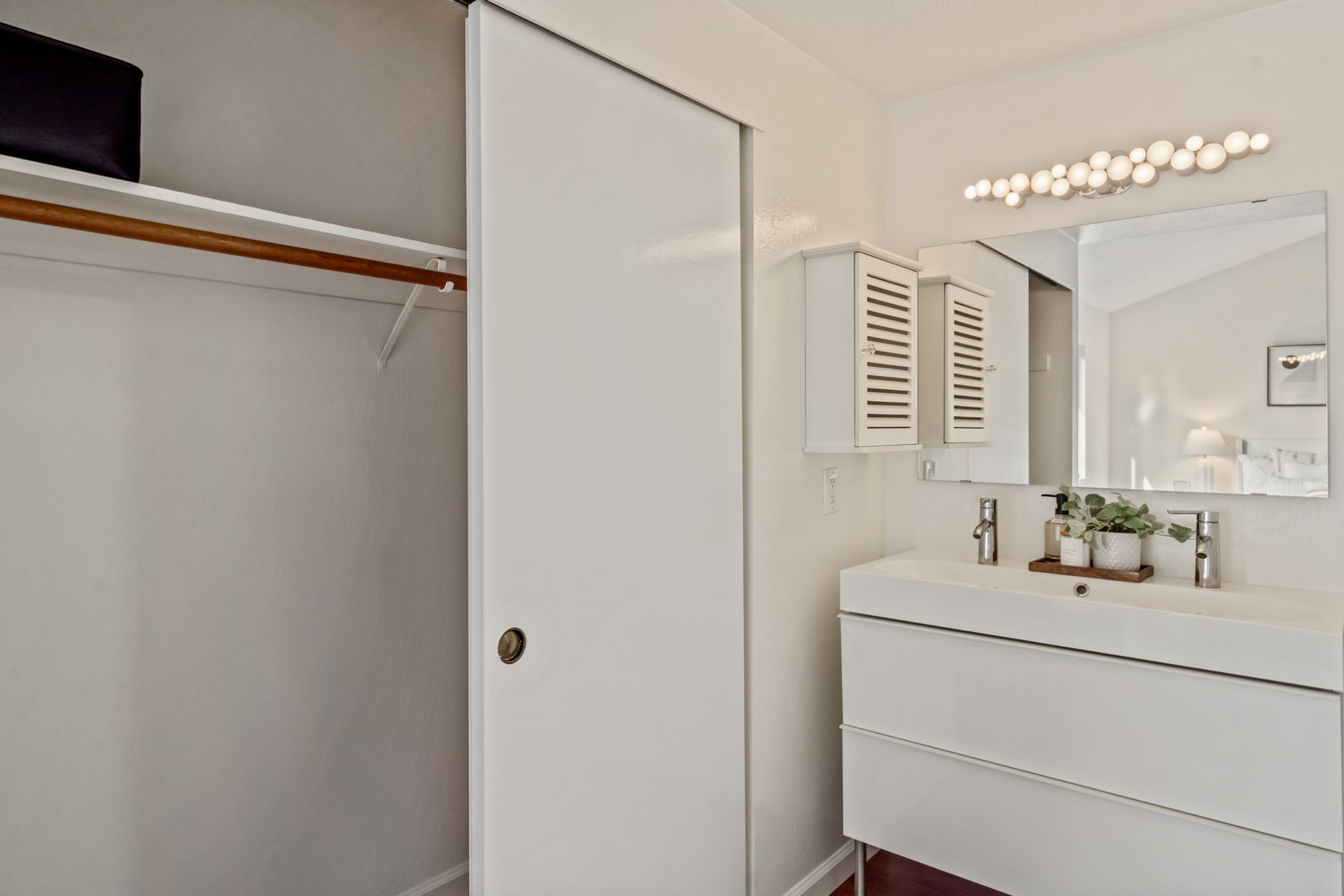 A bathroom with a sink , mirror and closet.