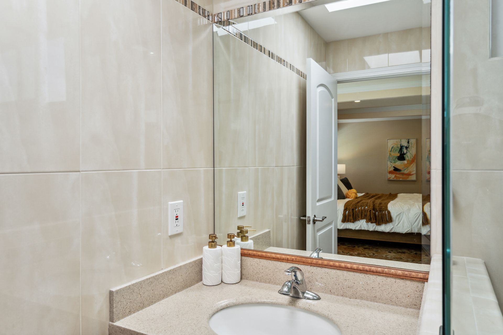 A bathroom with a sink and a large mirror.