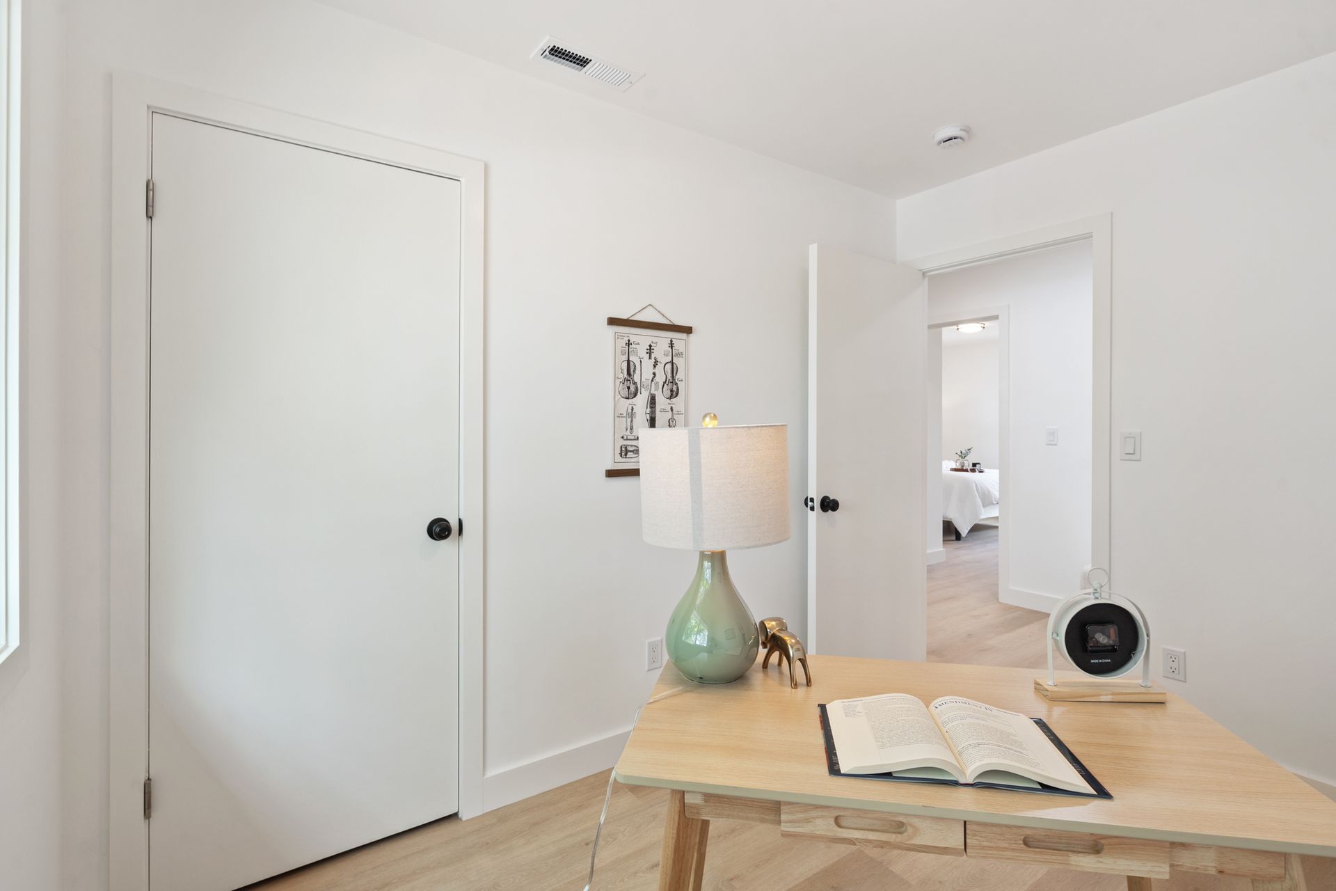 A desk with a lamp and a book on it in a room.