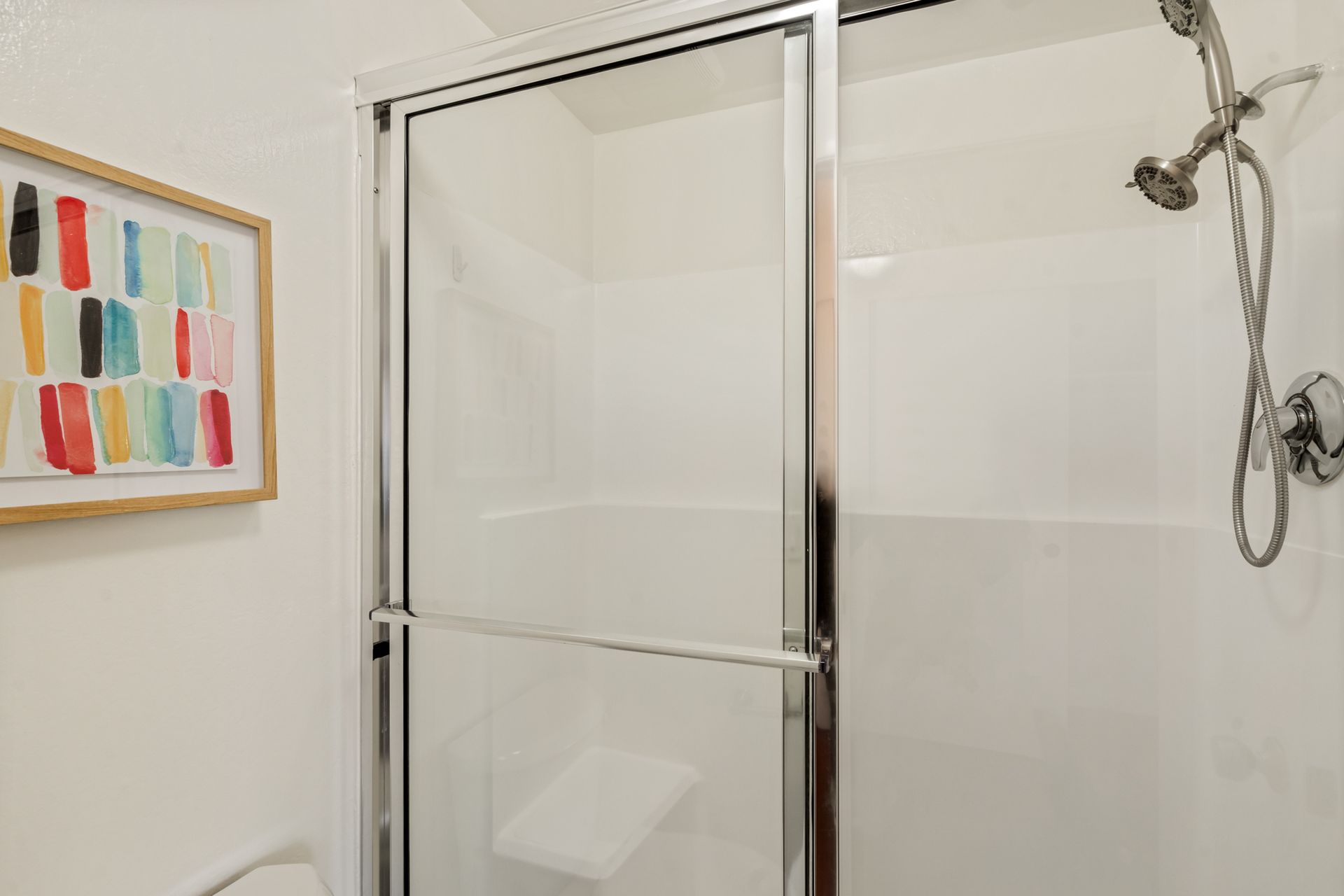 A bathroom with a shower and a picture on the wall.