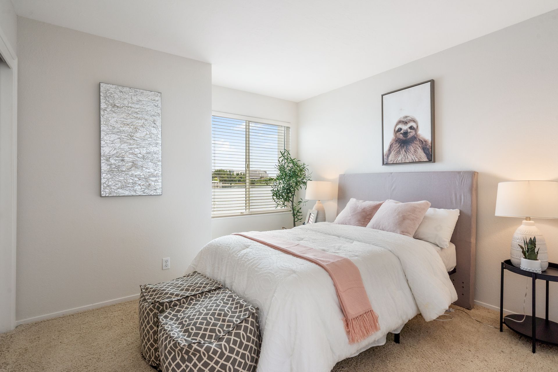 A bedroom with a bed , nightstand , lamps and a window.