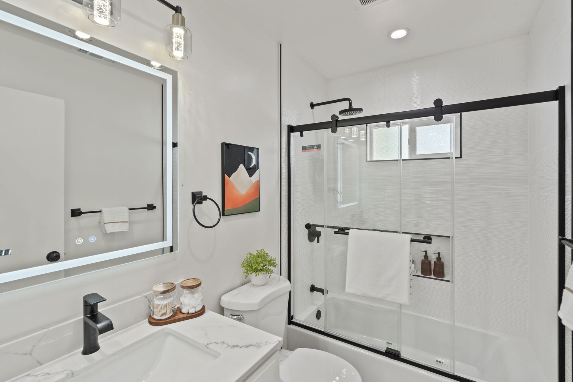 A bathroom with a sink , toilet , shower and mirror.