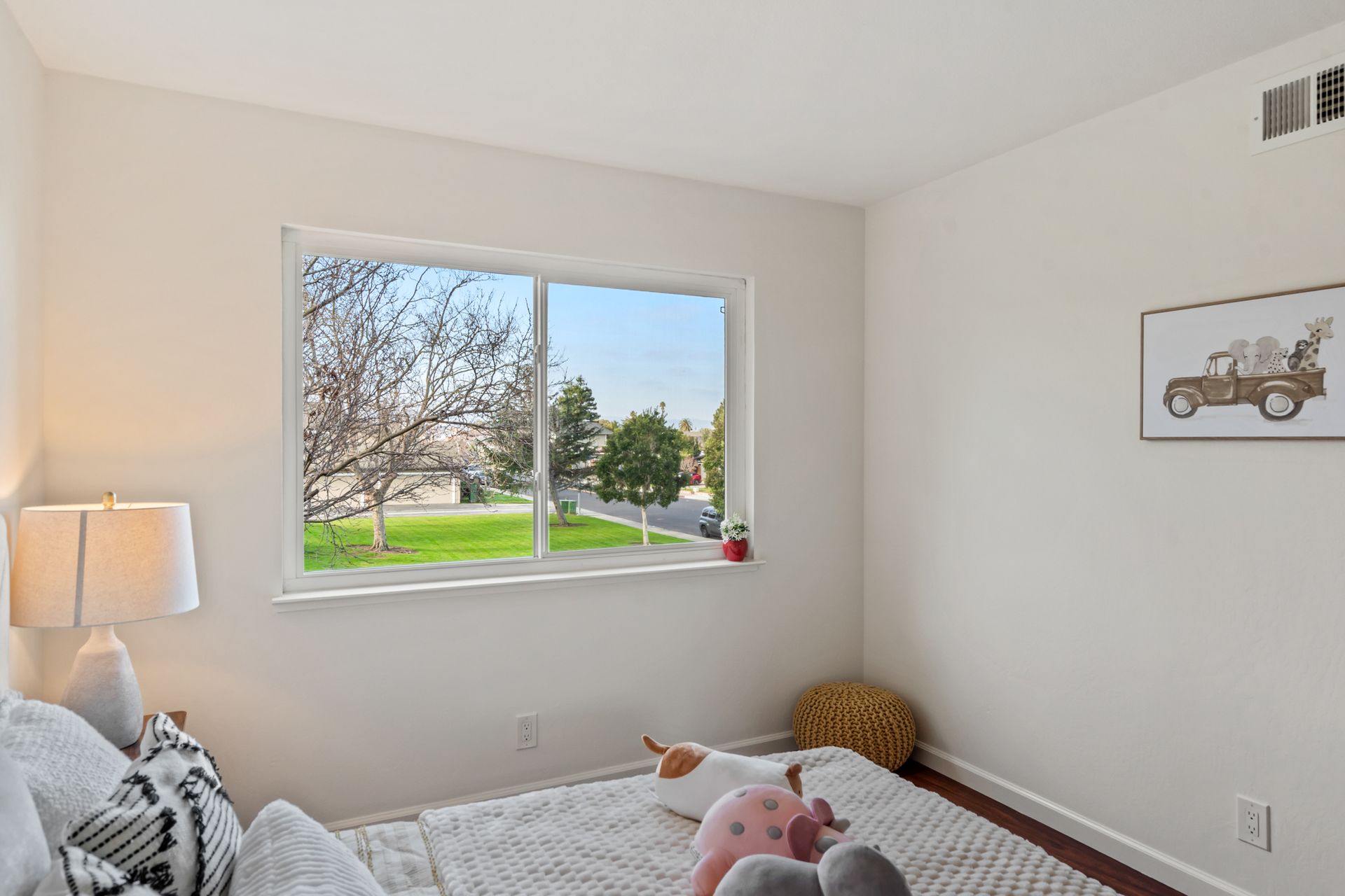 A bedroom with a bed and a window with a picture of a truck on the wall.