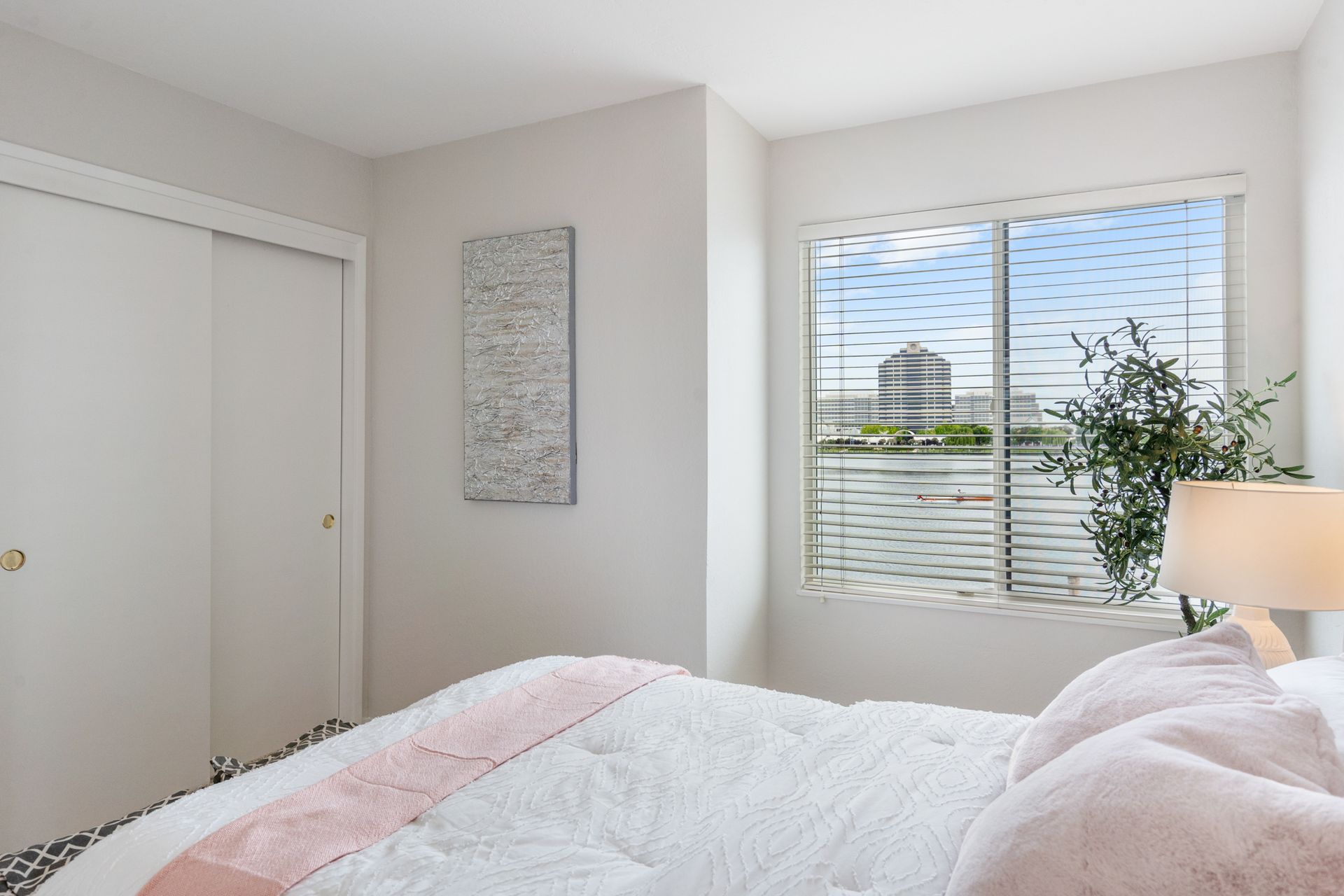 A bedroom with a large bed and a window with blinds.