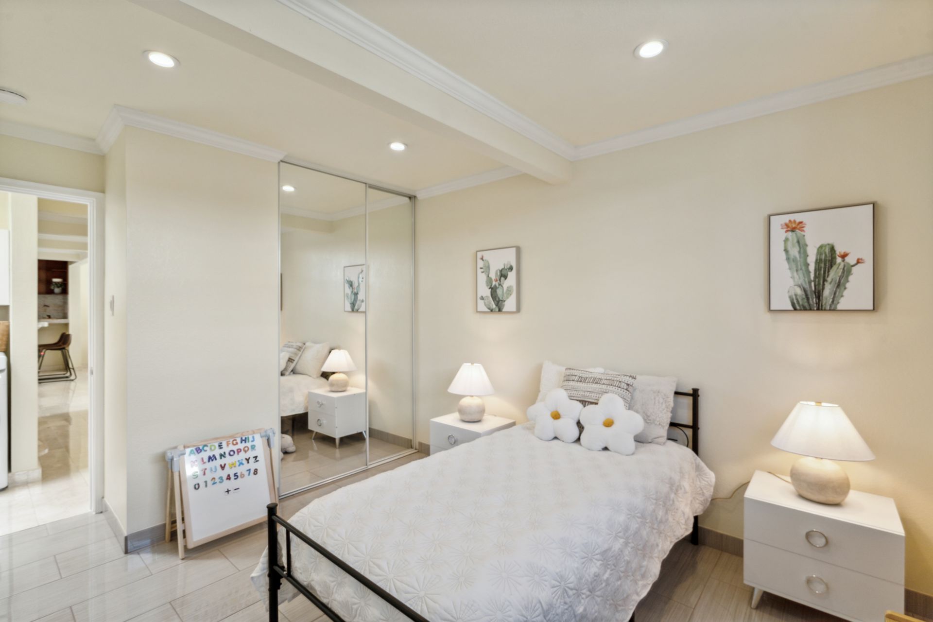 A bedroom with a bed , nightstands , lamps and a large mirrored wardrobe.