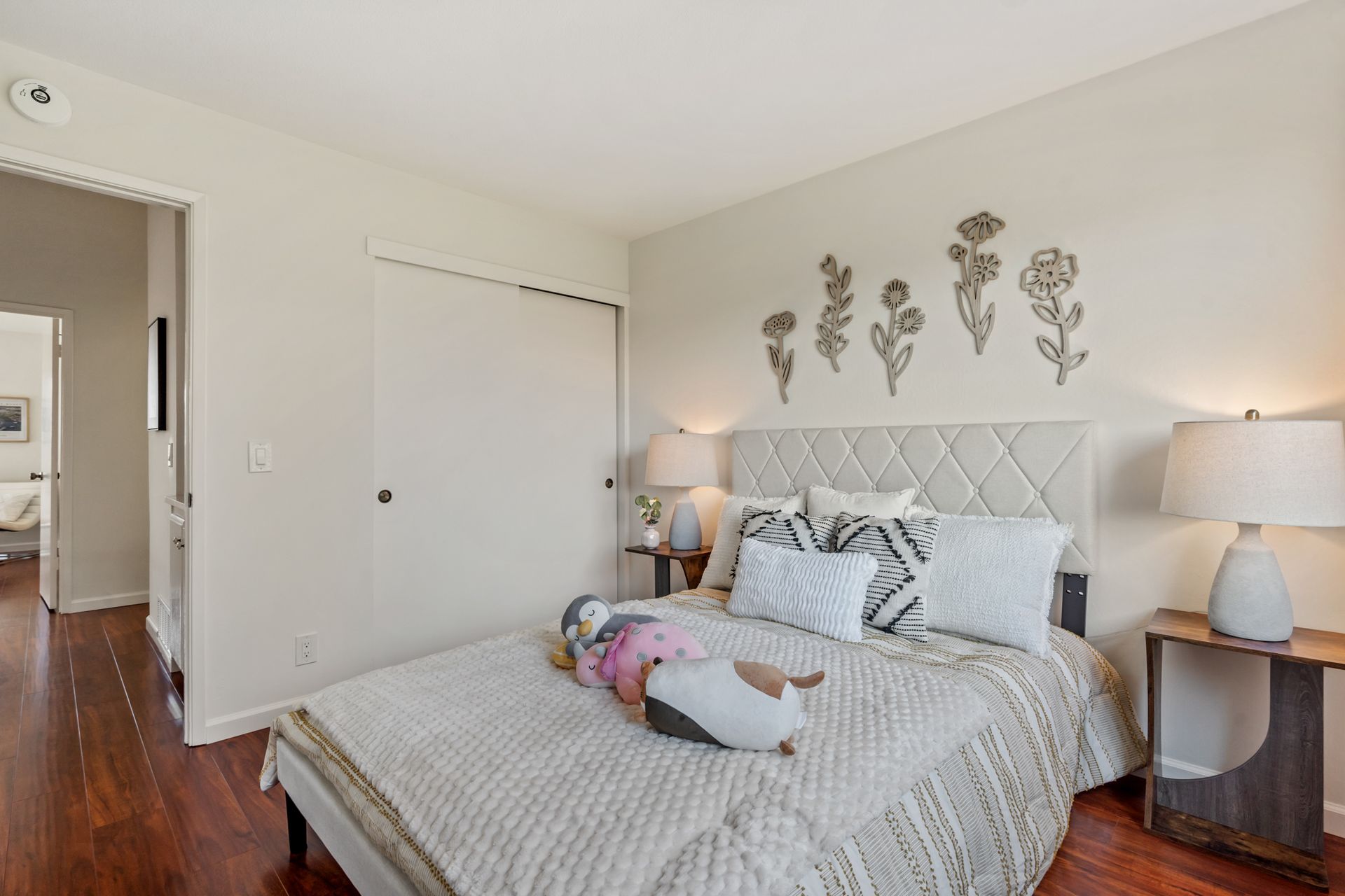 A bedroom with a bed , lamps , nightstands and a closet.