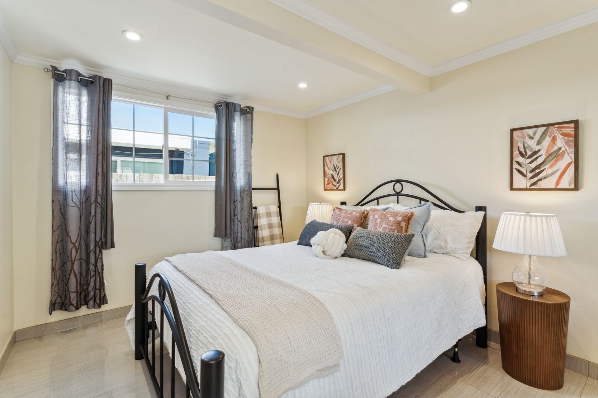 A bedroom with a bed , nightstand , lamp and window.