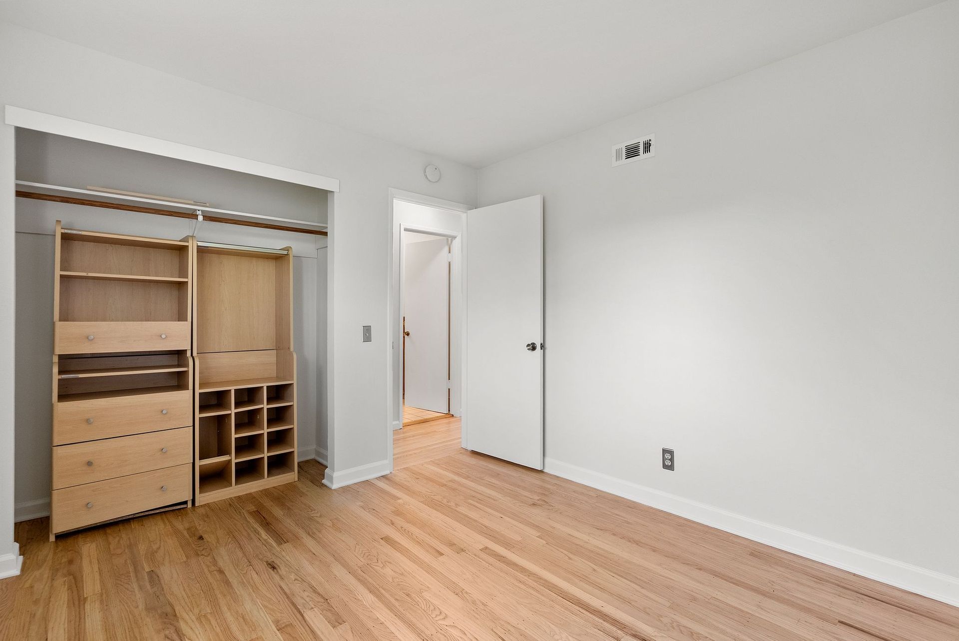 An empty bedroom with hardwood floors and a walk in closet.