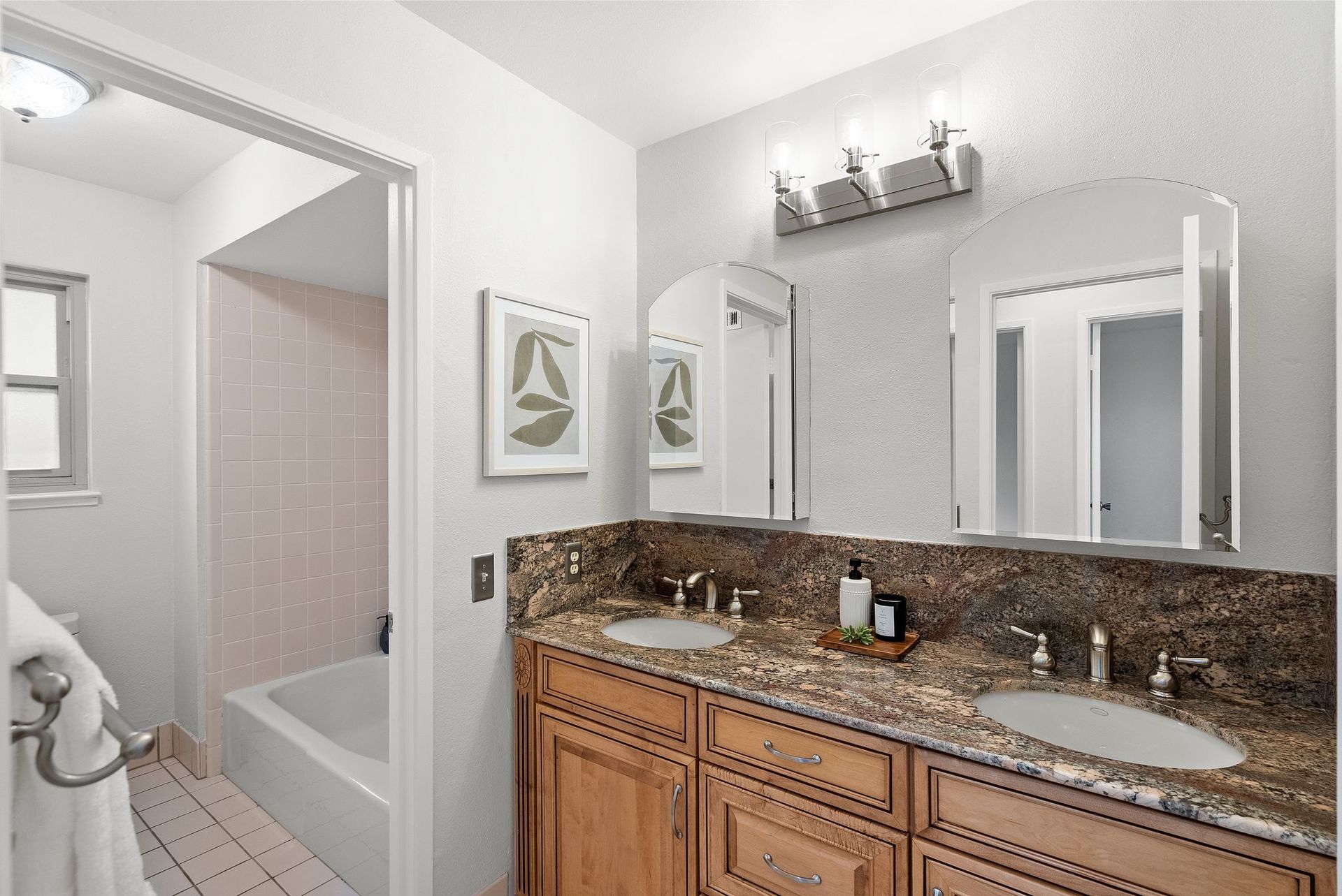 A bathroom with two sinks , two mirrors and a bathtub.