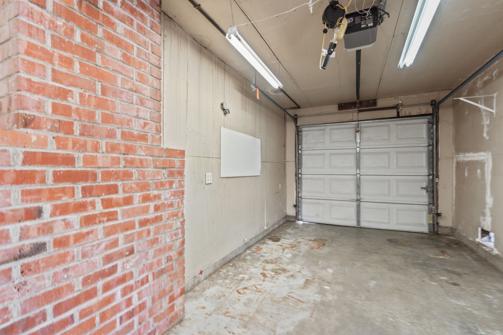 A garage with a brick wall and a white garage door.