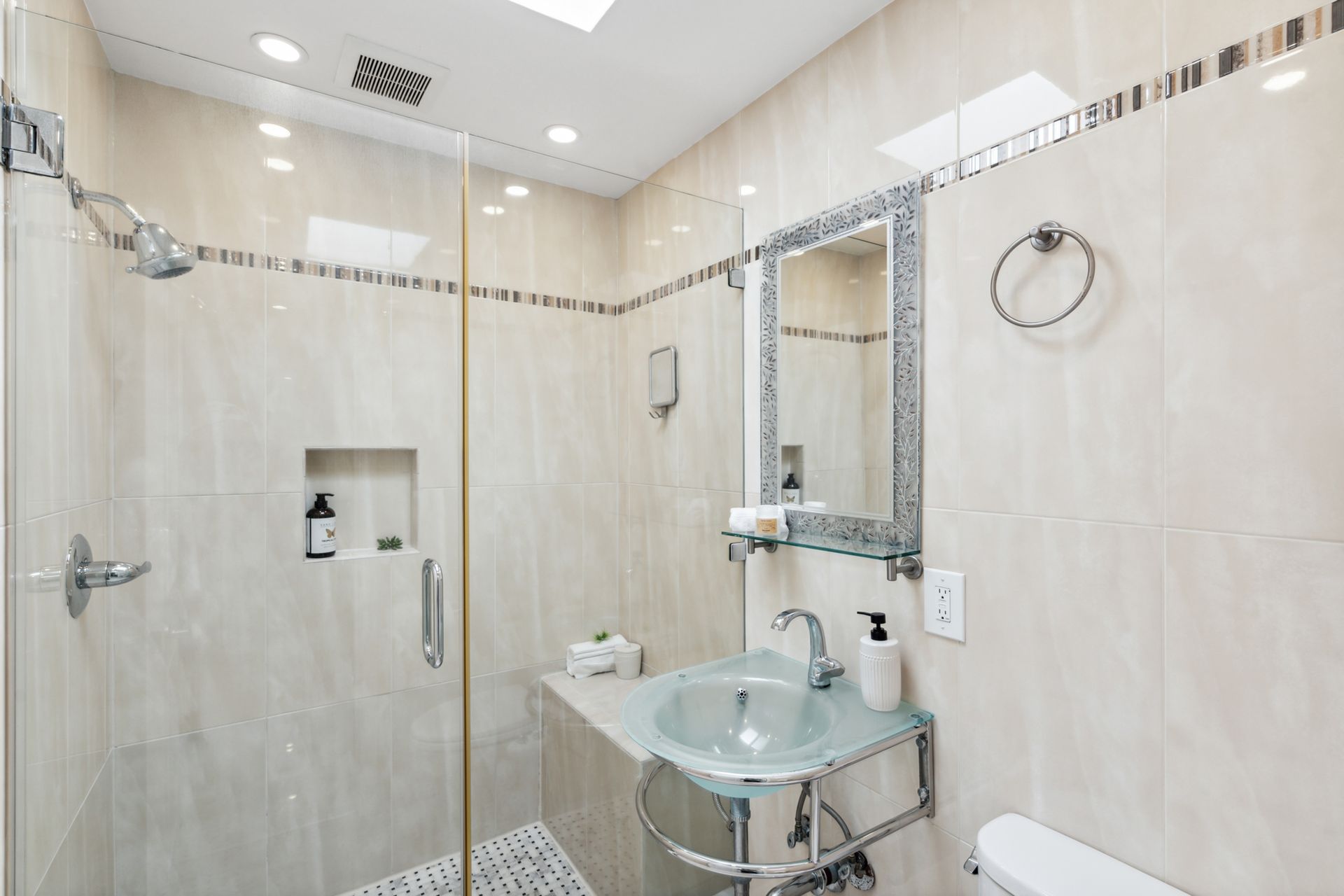 A bathroom with a sink , toilet , shower and mirror.
