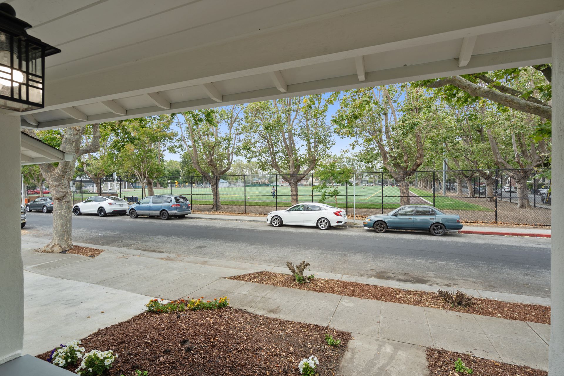 A white car is parked on the side of the road in front of a house.